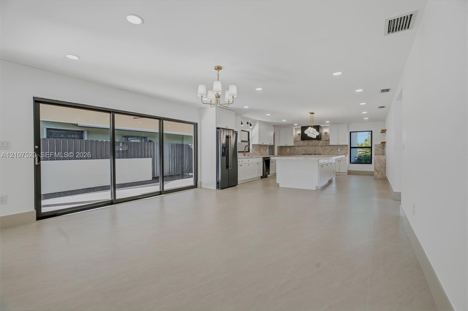 Kitchen featuring shaker-style cabinetry, an expansive center island with stone-finish countertops, matte black appliances, modern multi-globe chandel