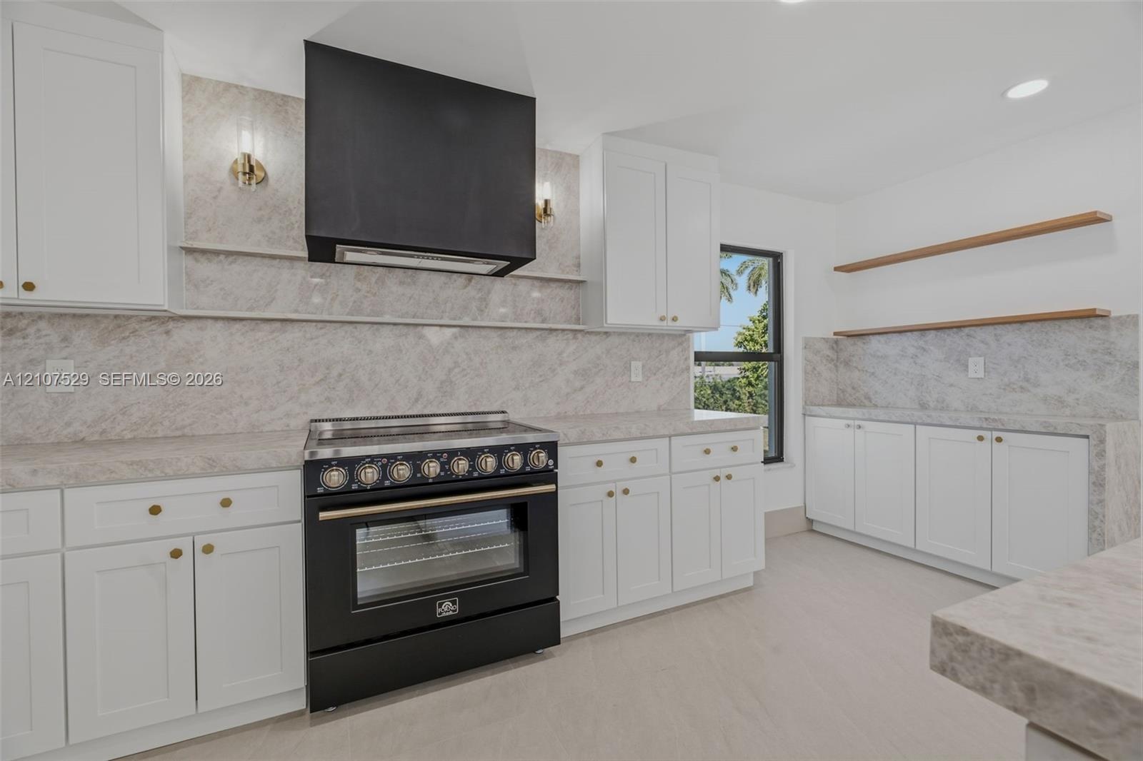 Kitchen featuring white cabinetry, stone-surface countertops, central island, black refrigerator, and multi-globe chandelier lighting