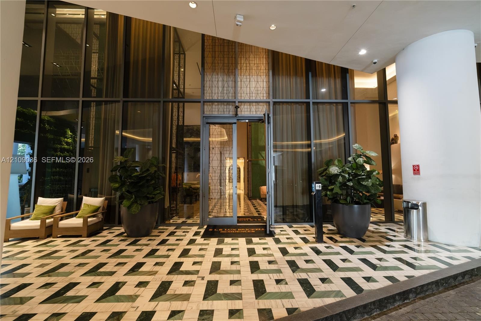 Grand entrance featuring floor-to-ceiling glass paneling, geometric stone tile flooring, and integrated recessed lighting