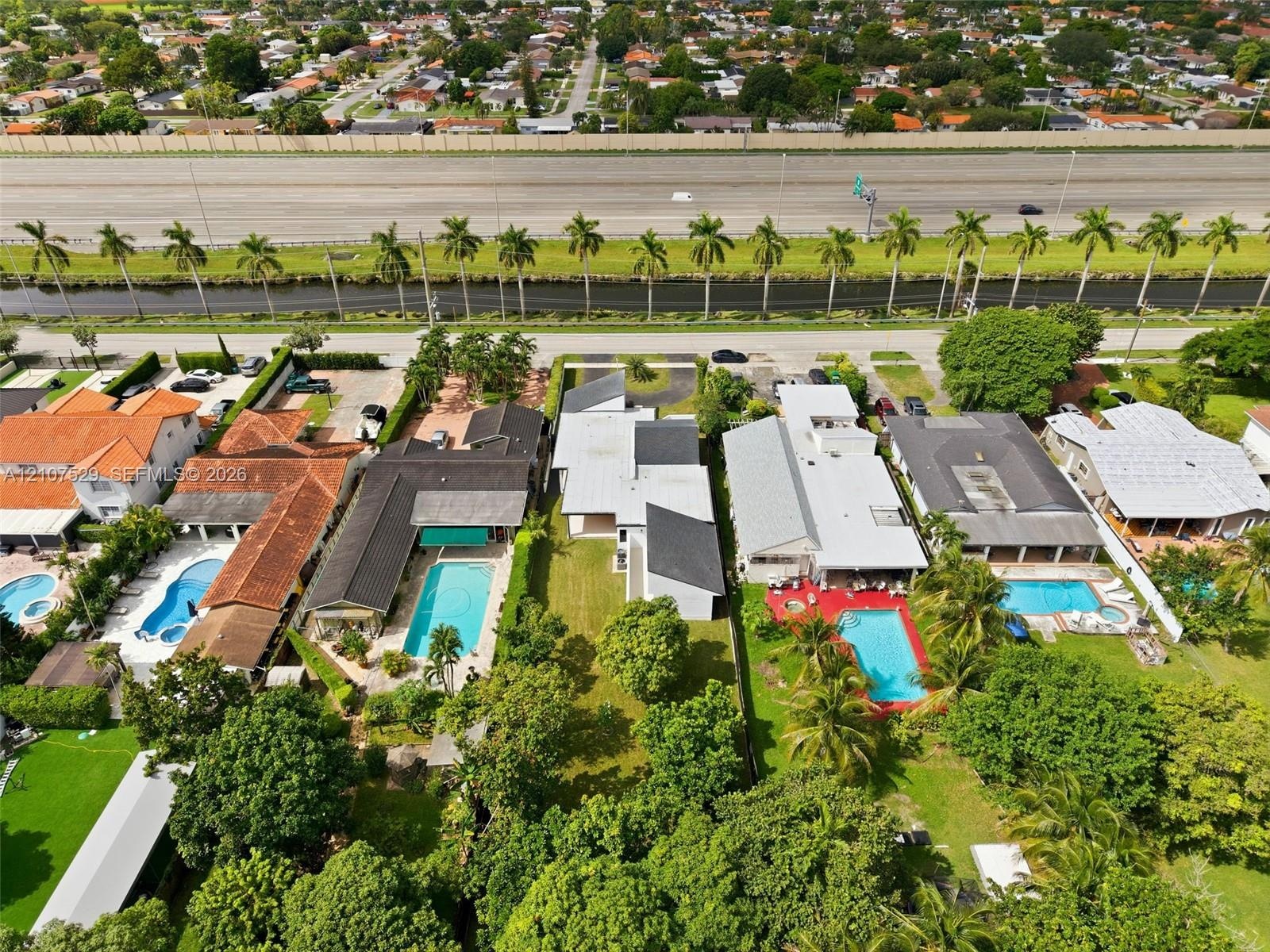 Expansive lot featuring a manicured lawn, perimeter privacy hedging, and mature trees