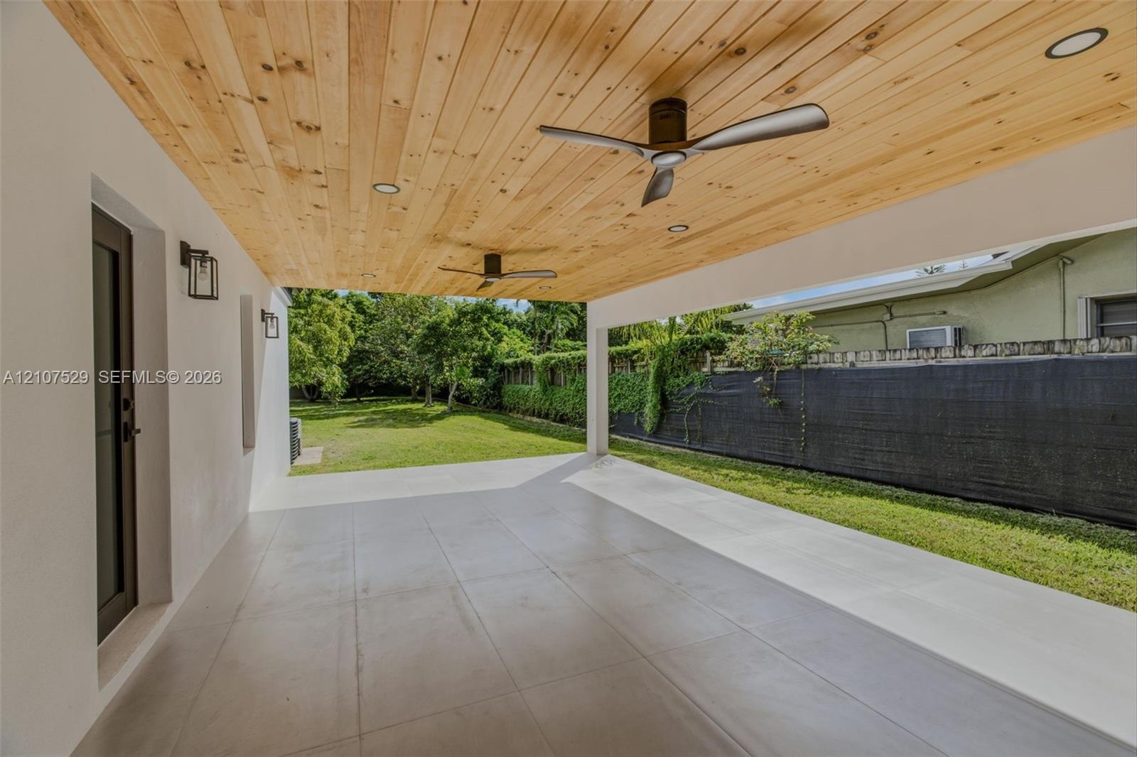 Neutral-toned flooring, multi-light chandelier, recessed ceiling lighting, and expansive glass sliding doors with black frames