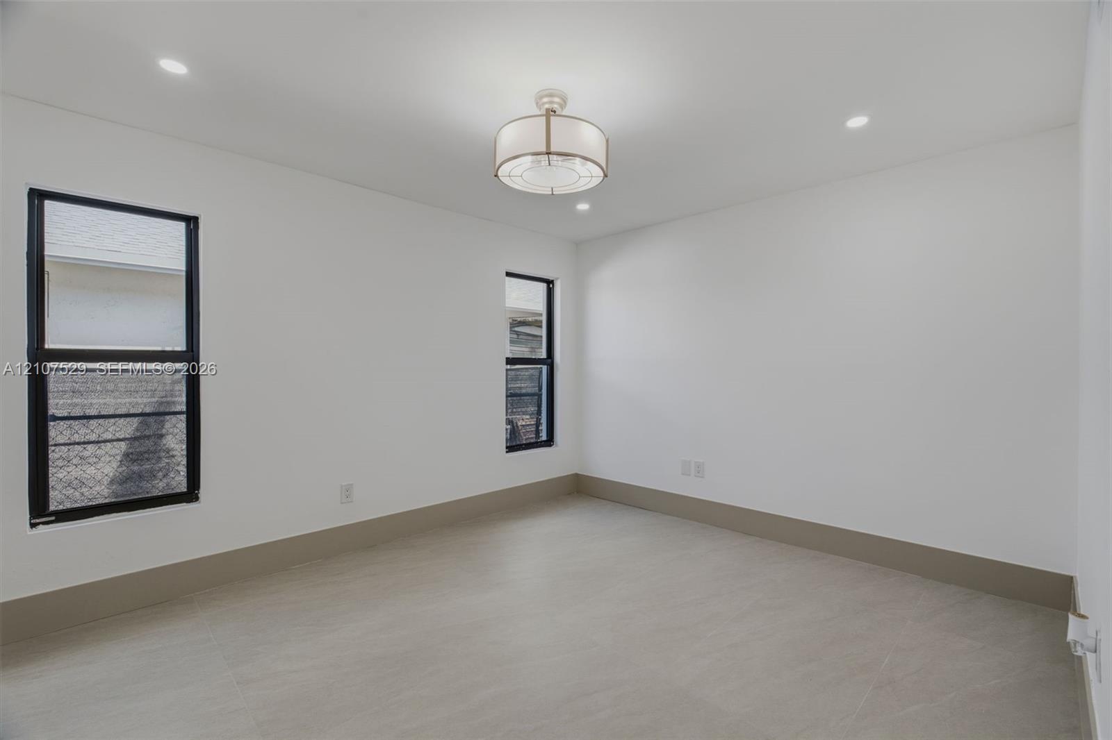 Neutral interior featuring oversized tile flooring, recessed lighting, a modern drum ceiling fixture, and custom-painted six-panel interior and slidin
