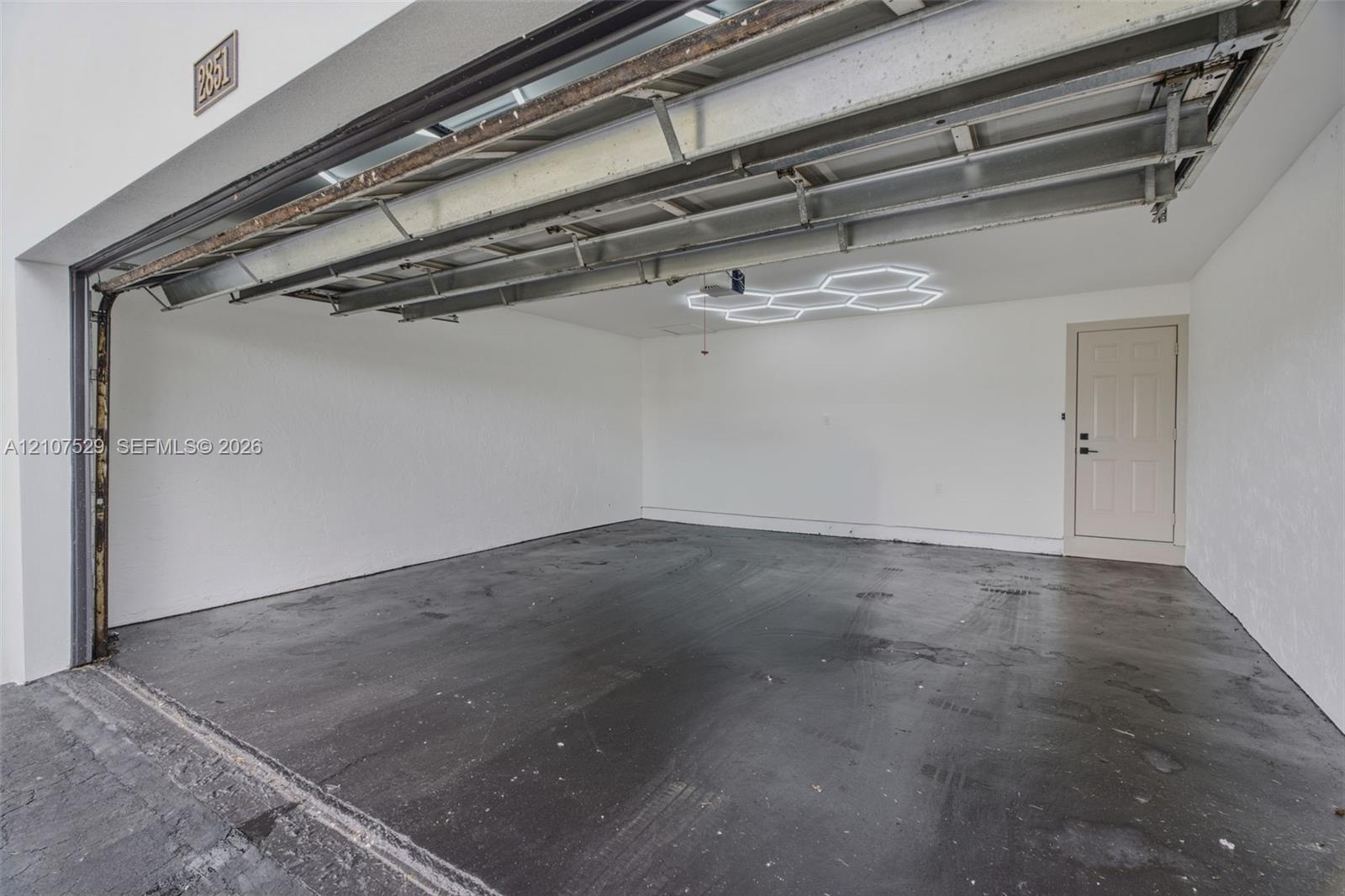 Multi-car garage featuring a concrete floor, finished white walls, and a hexagonal LED ceiling fixture