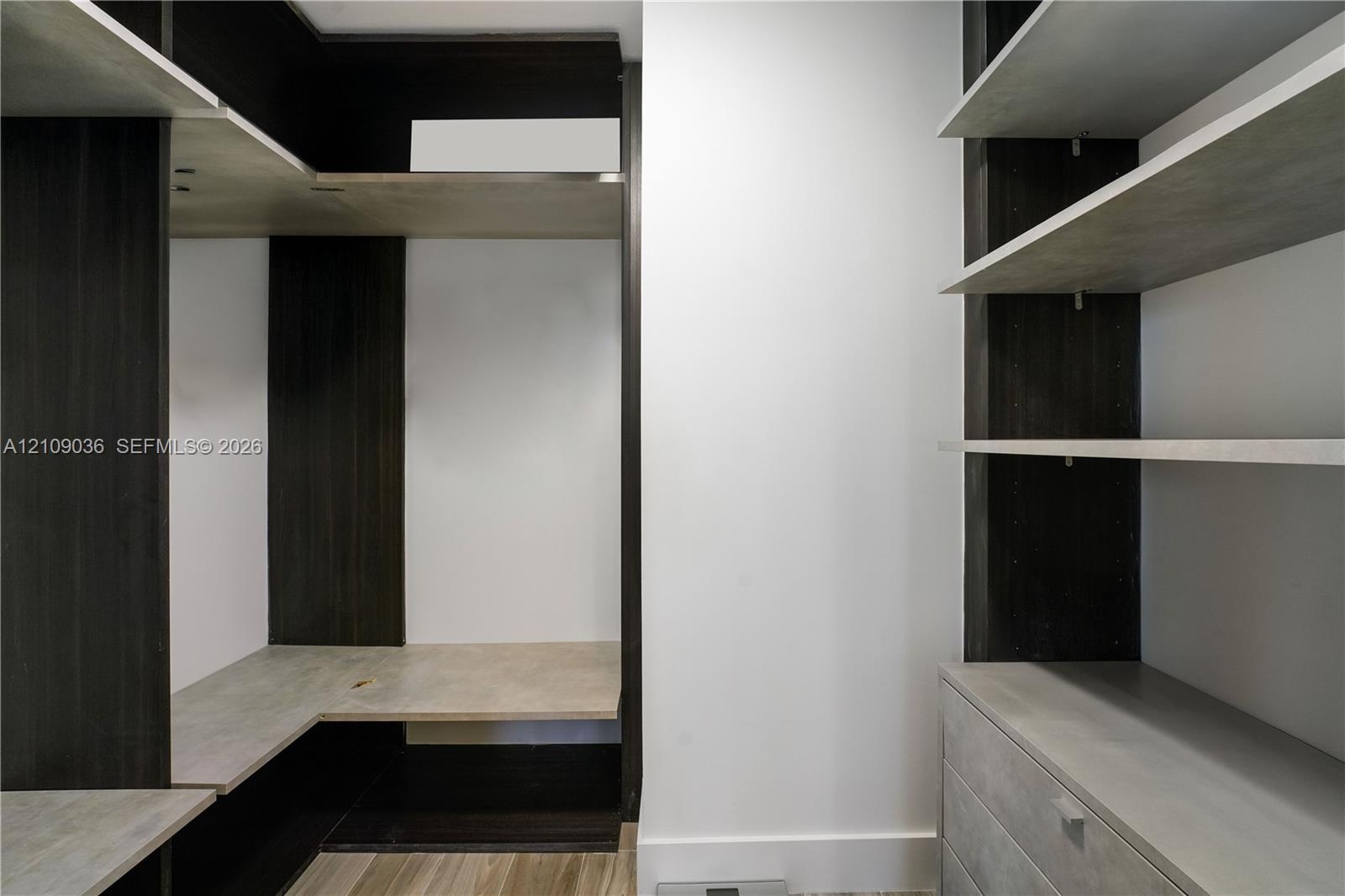 Custom built-in storage system featuring dark wood-tone cabinetry, multiple open shelving tiers, integrated drawer units, and light-toned horizontal s