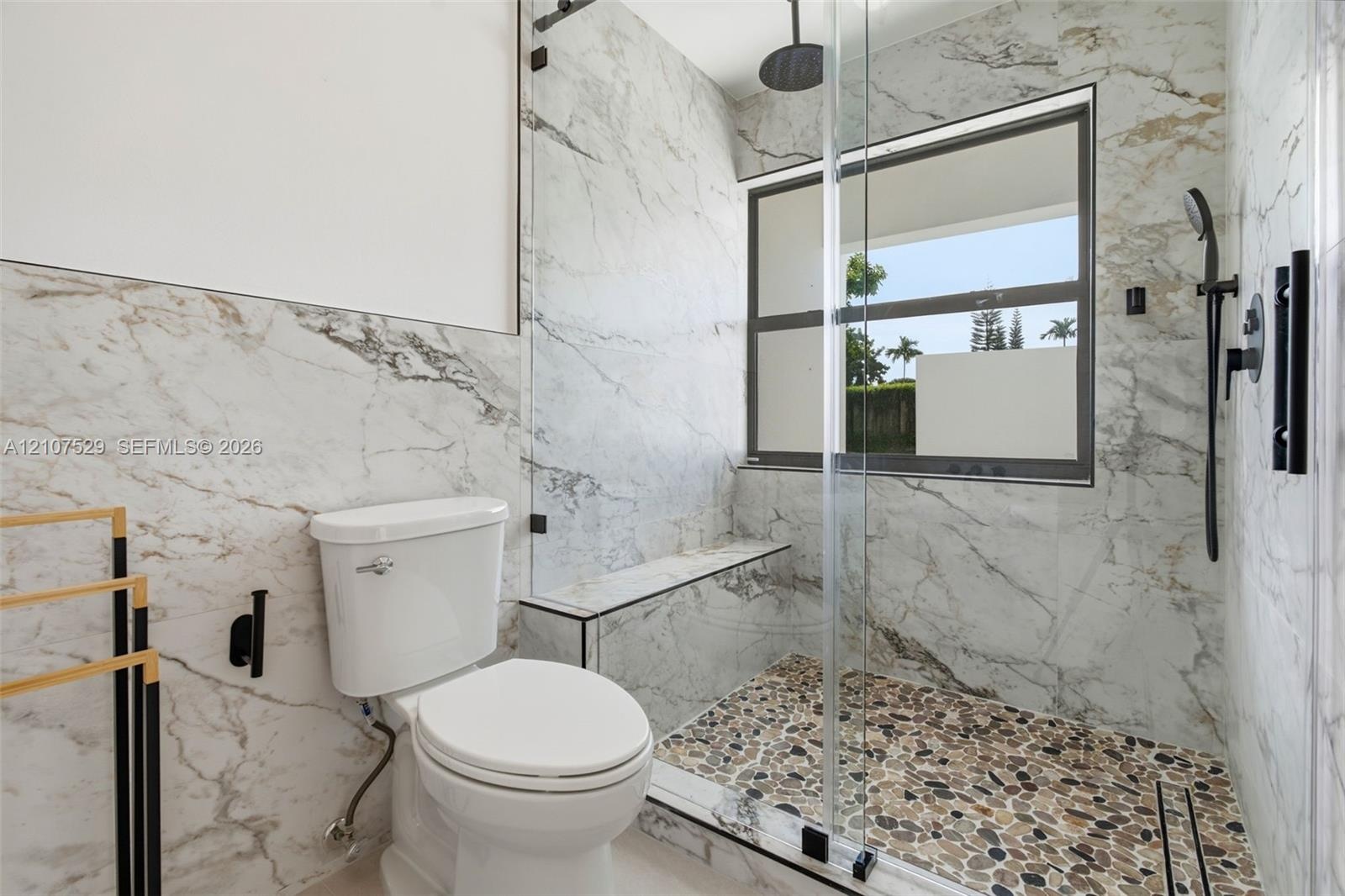 Dual-vanity cabinetry with stone-finish countertops, arched vanity mirrors, multi-bulb lighting, wall-mounted matte black faucet, and a freestanding s