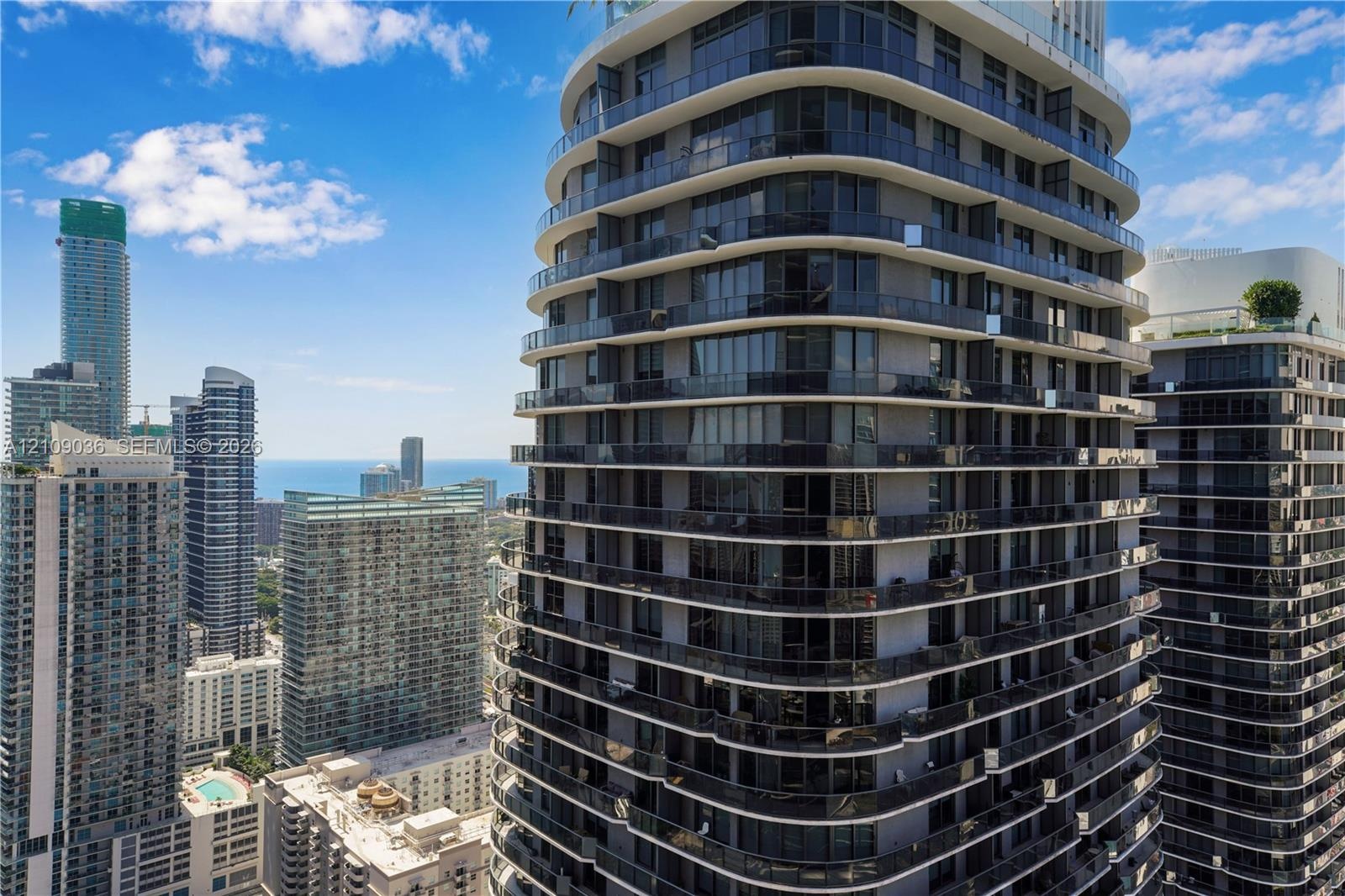High-rise glass and concrete exterior featuring wraparound balconies, floor-to-ceiling windows, and a curved architectural design