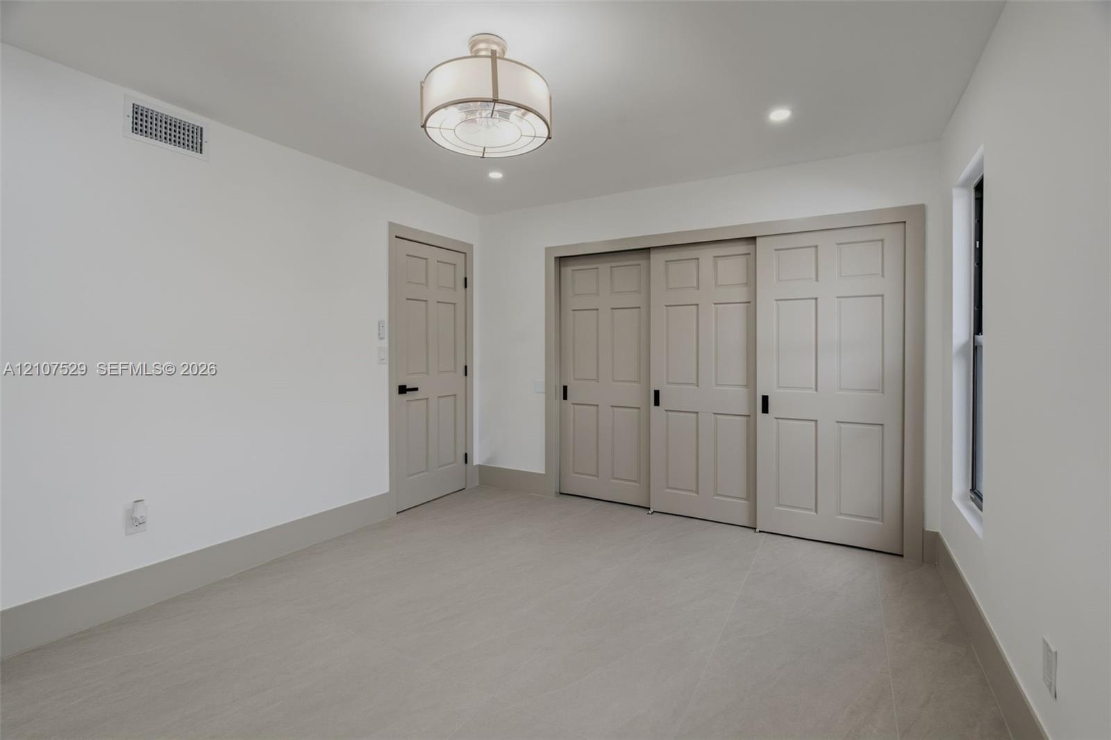 Covered patio featuring large-format porcelain tile flooring and smooth white stucco exterior wall finishes