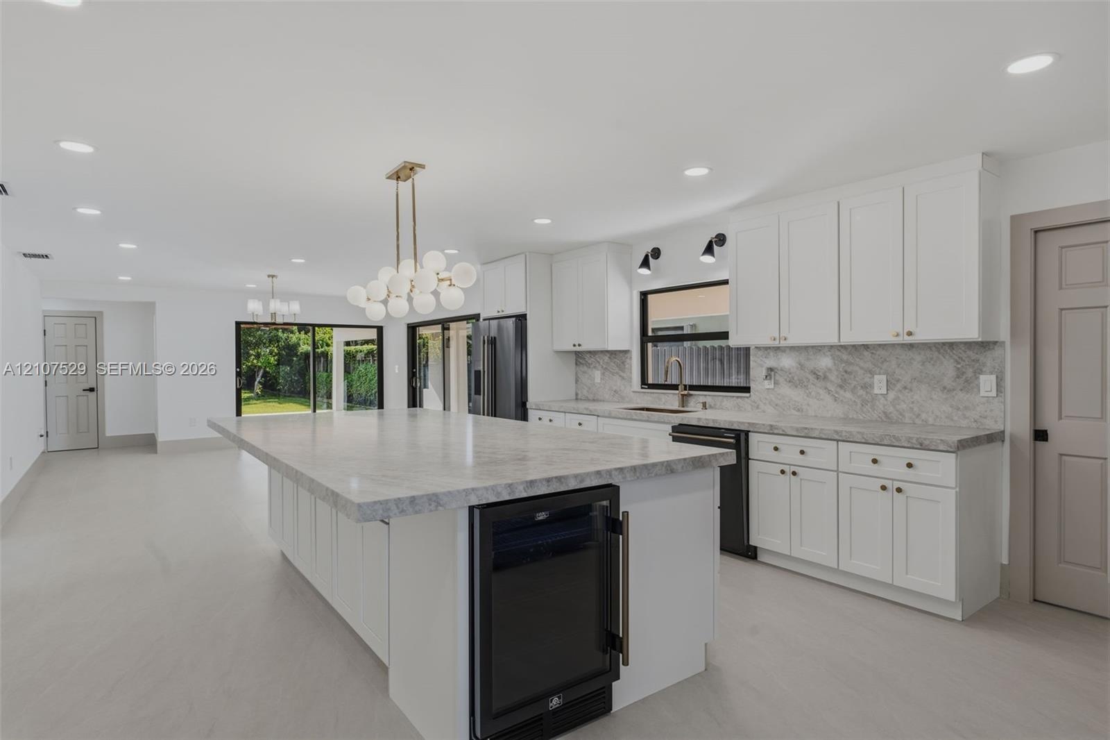 Kitchen featuring white cabinetry, stone-surface countertops, full-height stone backsplash, matte black appliances, and recessed lighting