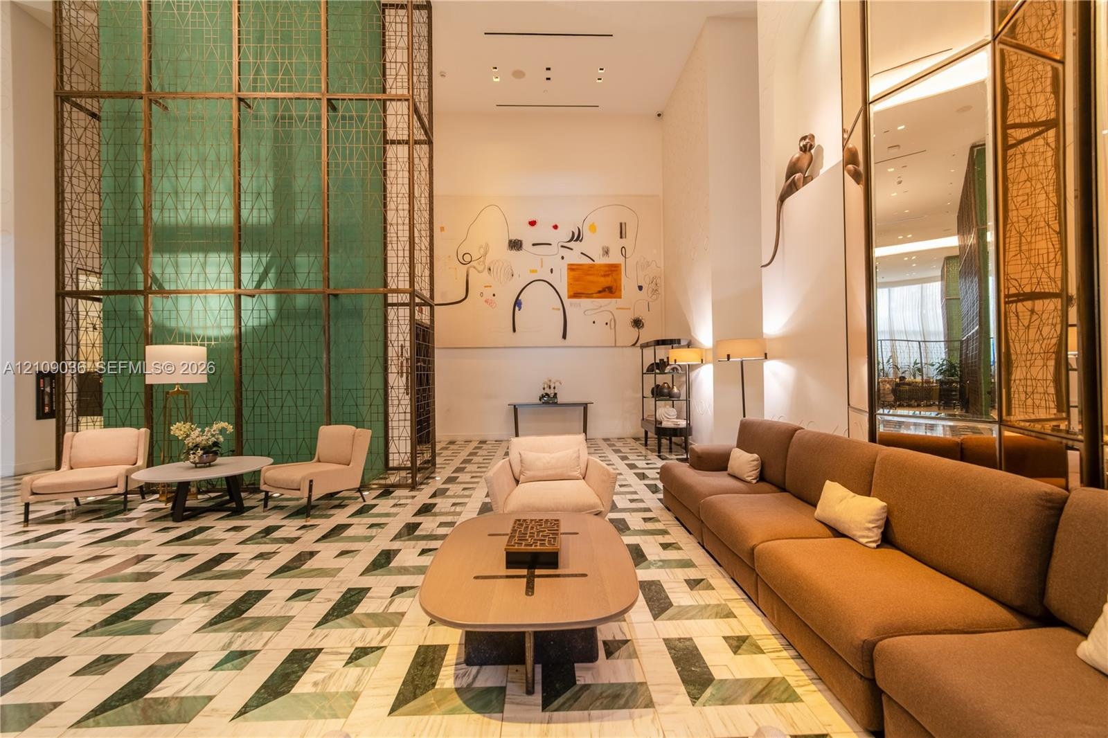 Grand lobby featuring expansive ceiling heights, geometric stone flooring, floor-to-ceiling decorative metal screening, mirrored wall panels, and rece