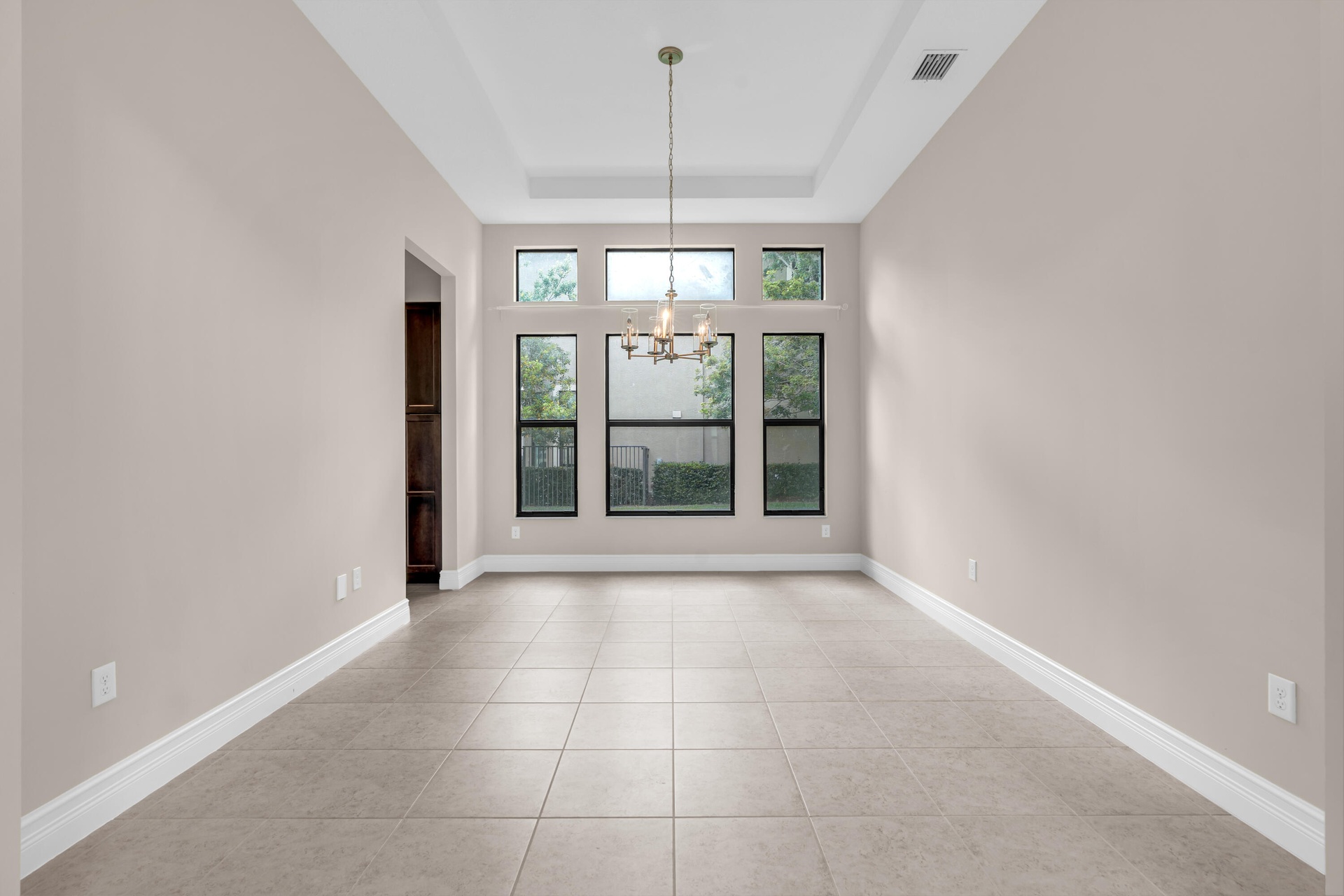 Bright, open room featuring soaring ceilings with recessed lighting, large multi-pane windows flooding the space with natural light, and neutral tile 
