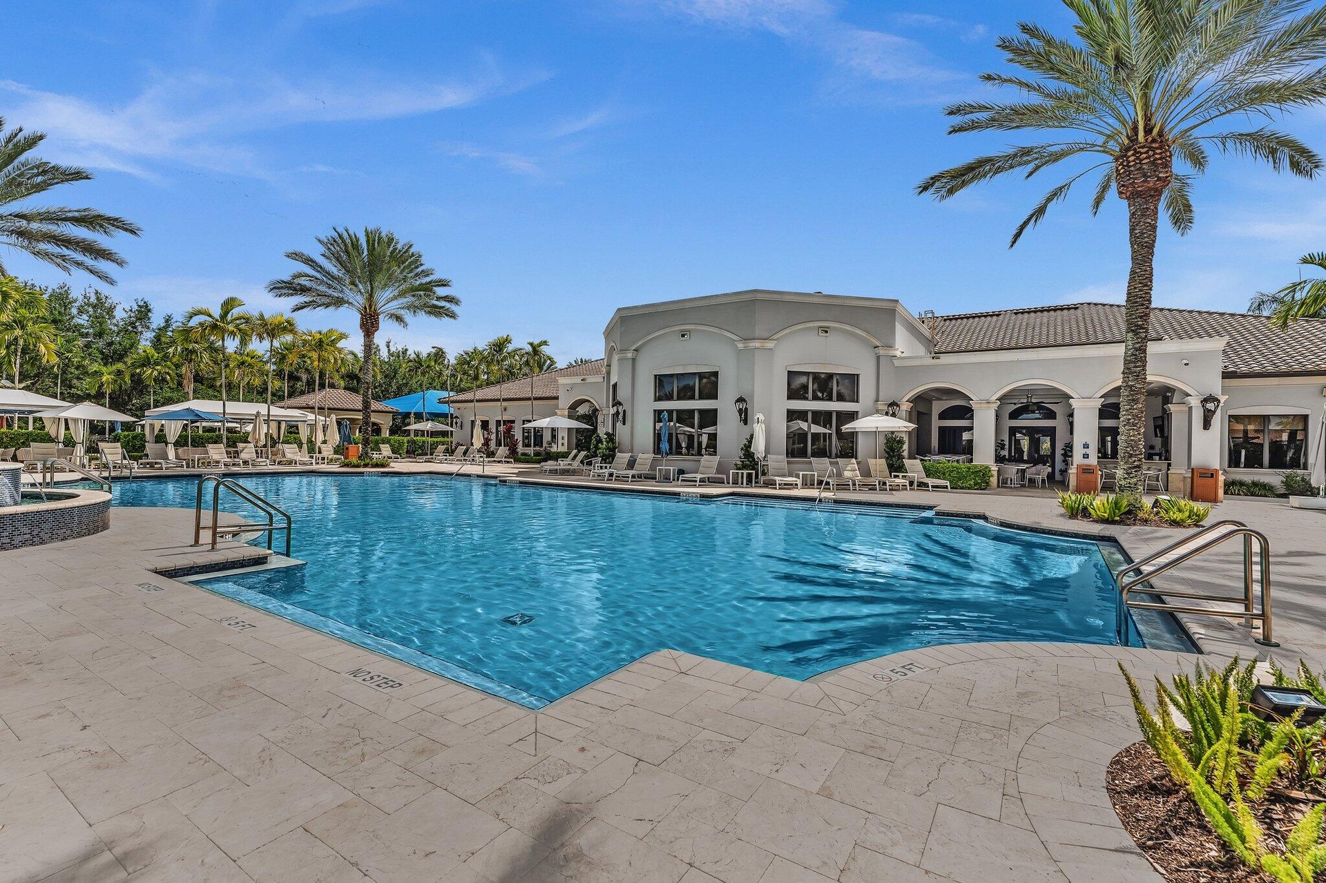 Resort-style swimming pool featuring a tiled deck, integrated spa, and surrounding palm trees