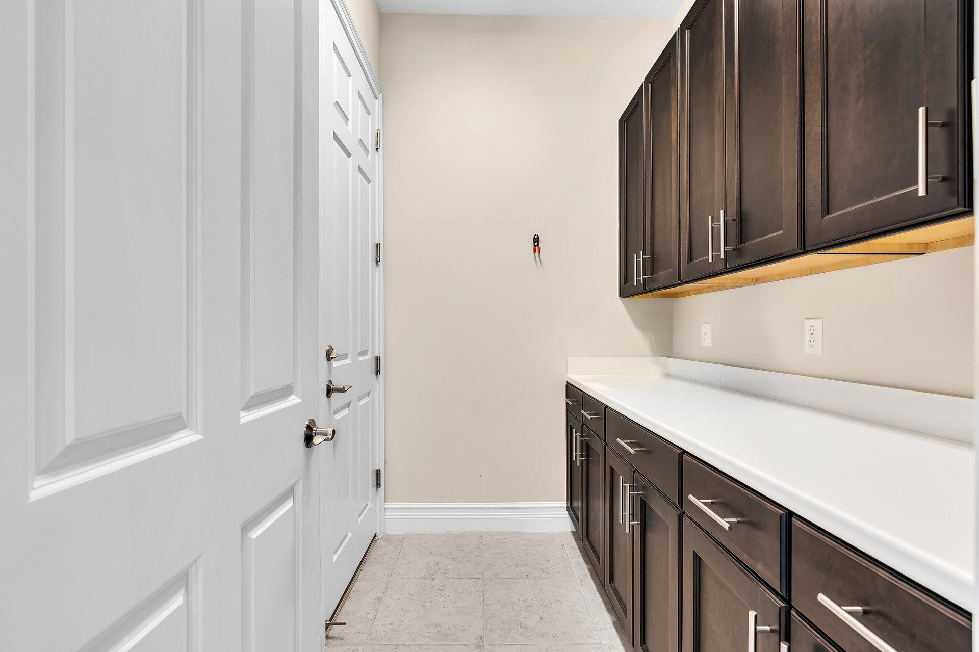 Built-in cabinetry with dark wood-finish doors and brushed nickel hardware, complemented by a white countertop and light wall paint