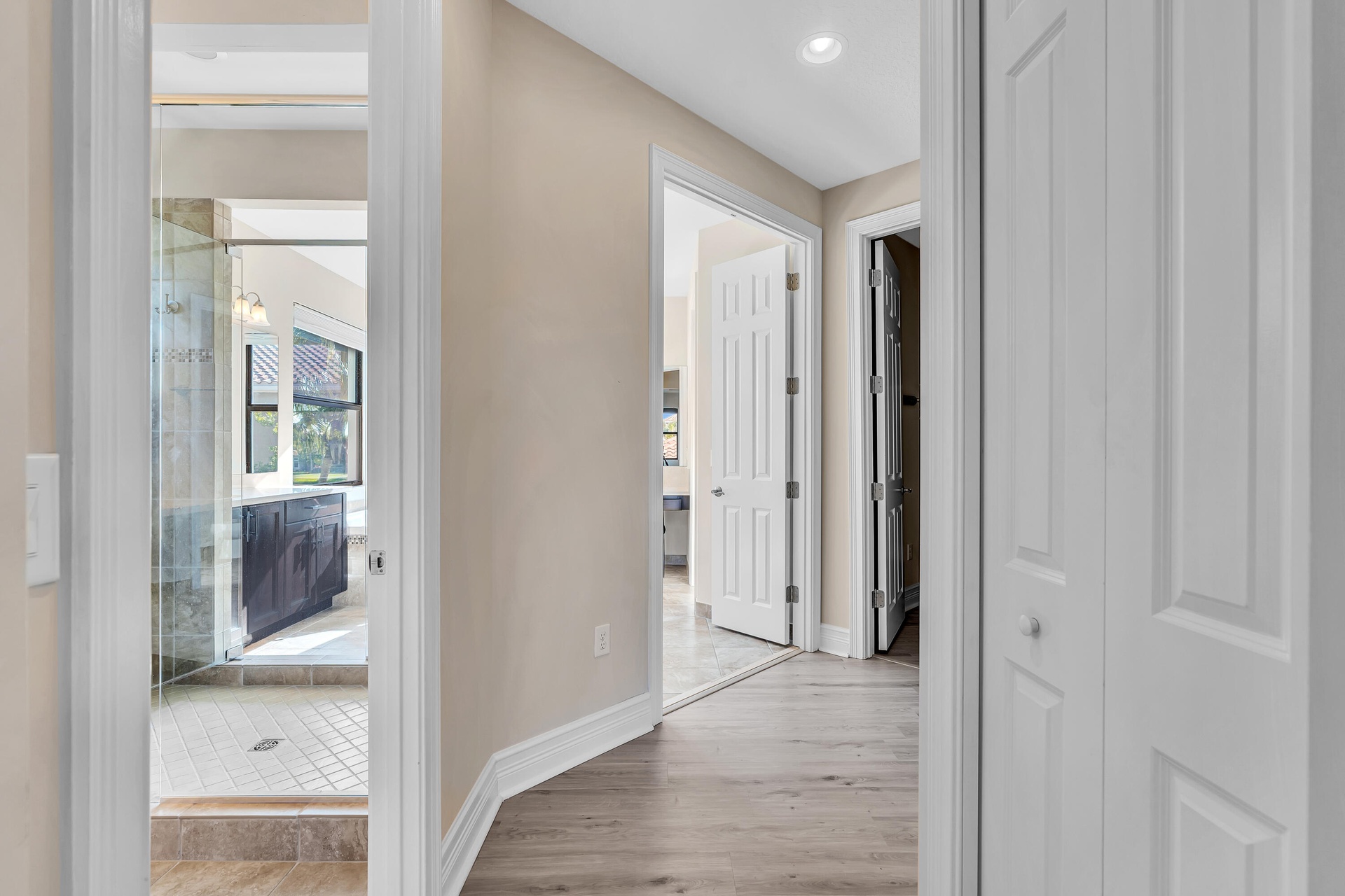 Hallway featuring wood-finish flooring, recessed lighting, and crisp white trim