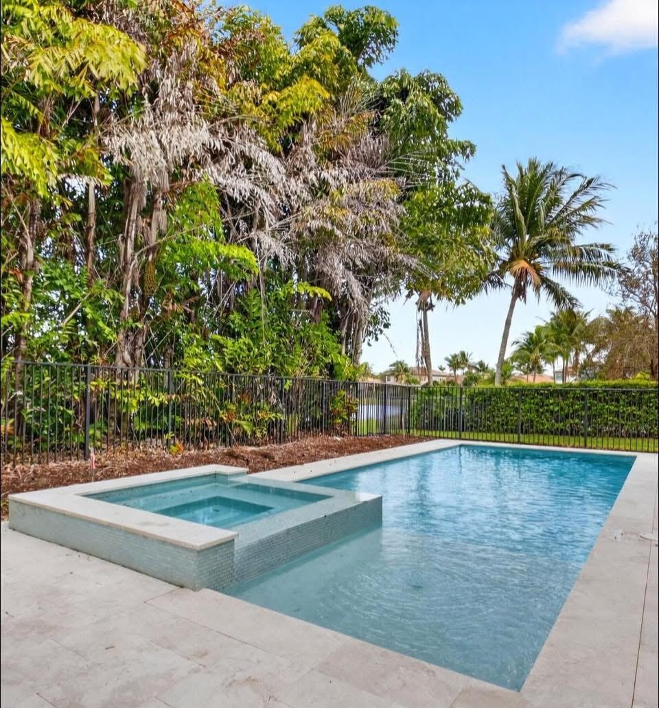 Swimming pool with integrated spa, surrounded by light-toned paving