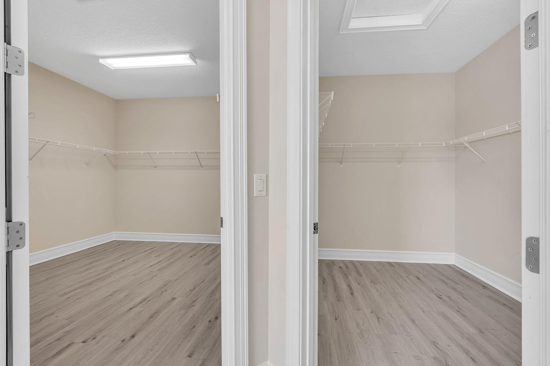 Dual walk-in closets featuring wood-finish flooring, white trim framing, and built-in shelving with rod systems