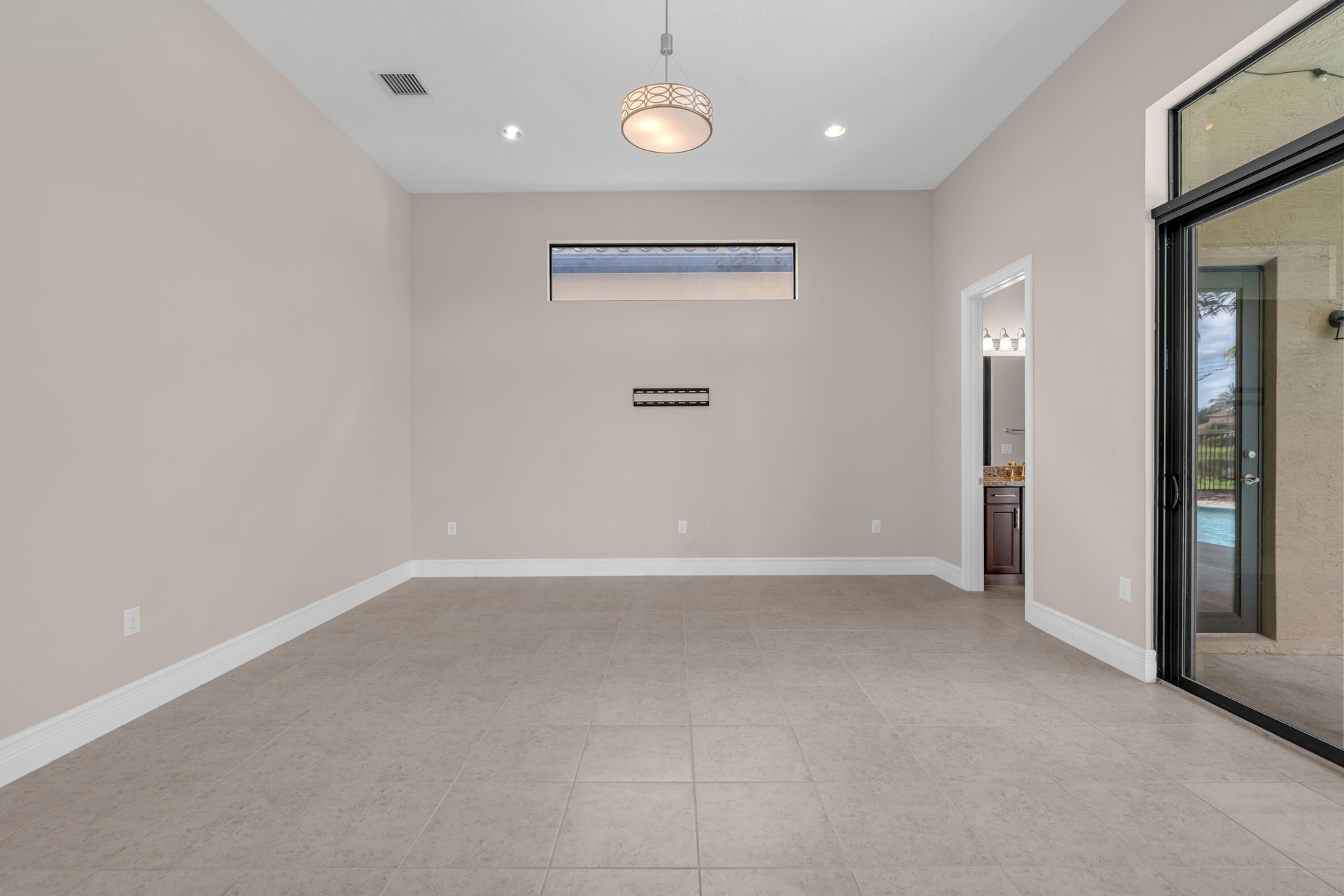 Spacious room featuring neutral tone walls, tile flooring, a horizontal window, recessed lighting, and a contemporary ceiling fixture