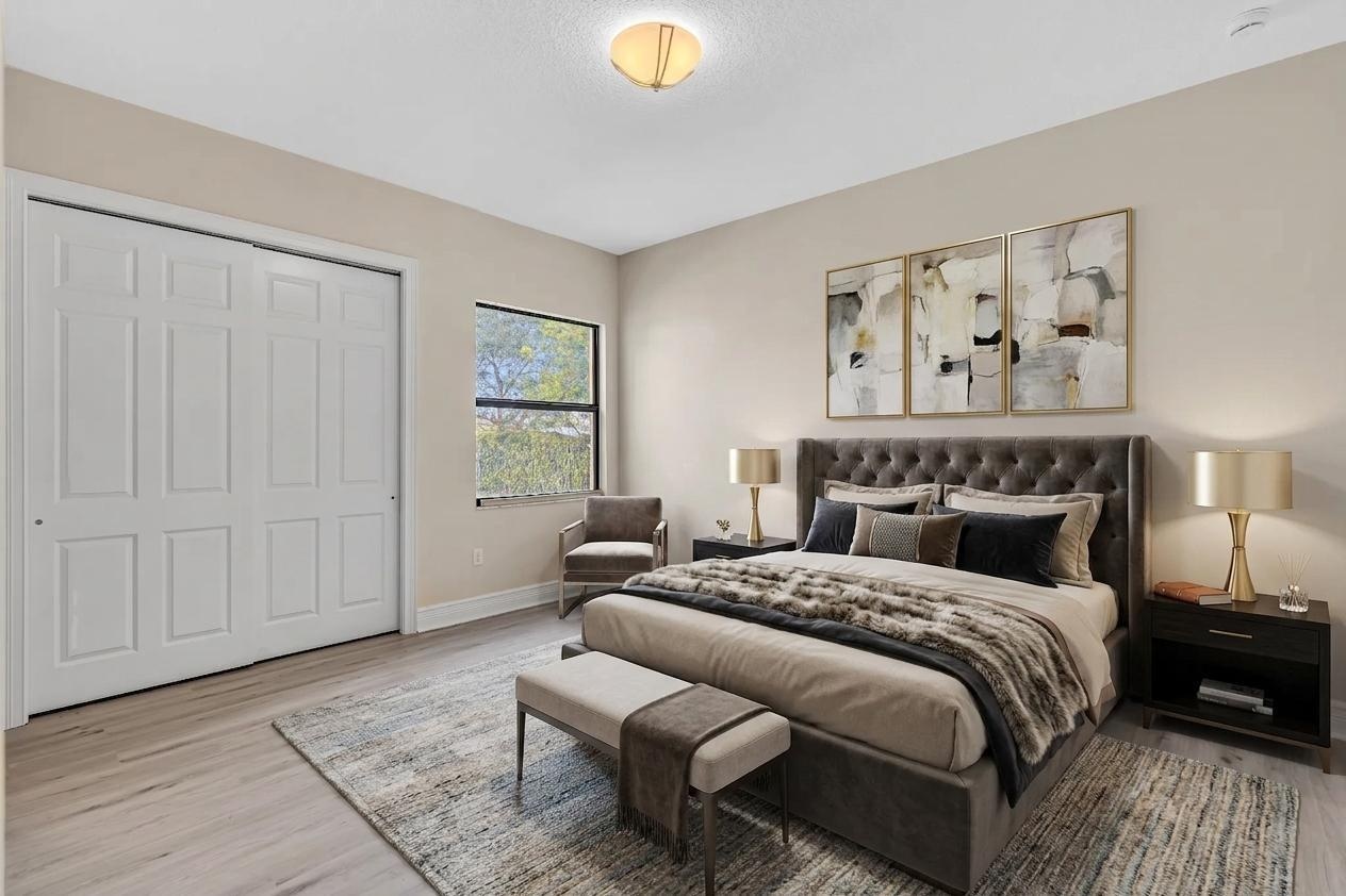Spacious primary bedroom featuring a tufted upholstered headboard, wood-finish flooring, and recessed ceiling lighting