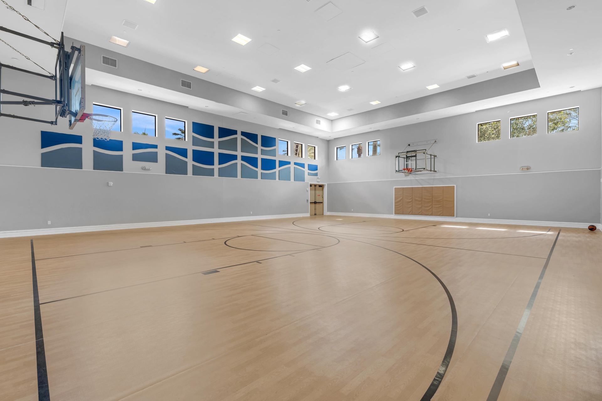 Dedicated indoor sports court featuring professional-grade wood-finish flooring with multiple court markings, recessed ceiling lighting throughout, la