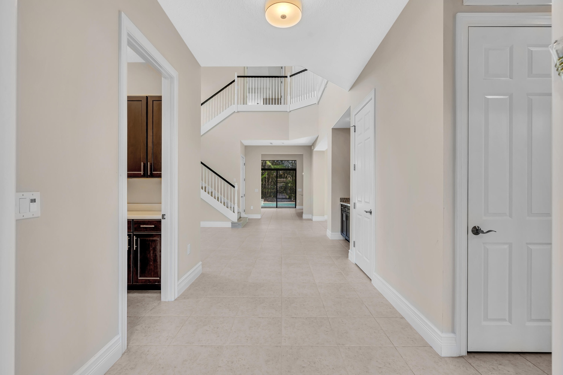 Bright two-story foyer featuring soaring ceilings, a curved staircase with white railings, neutral tile flooring throughout, and abundant natural ligh