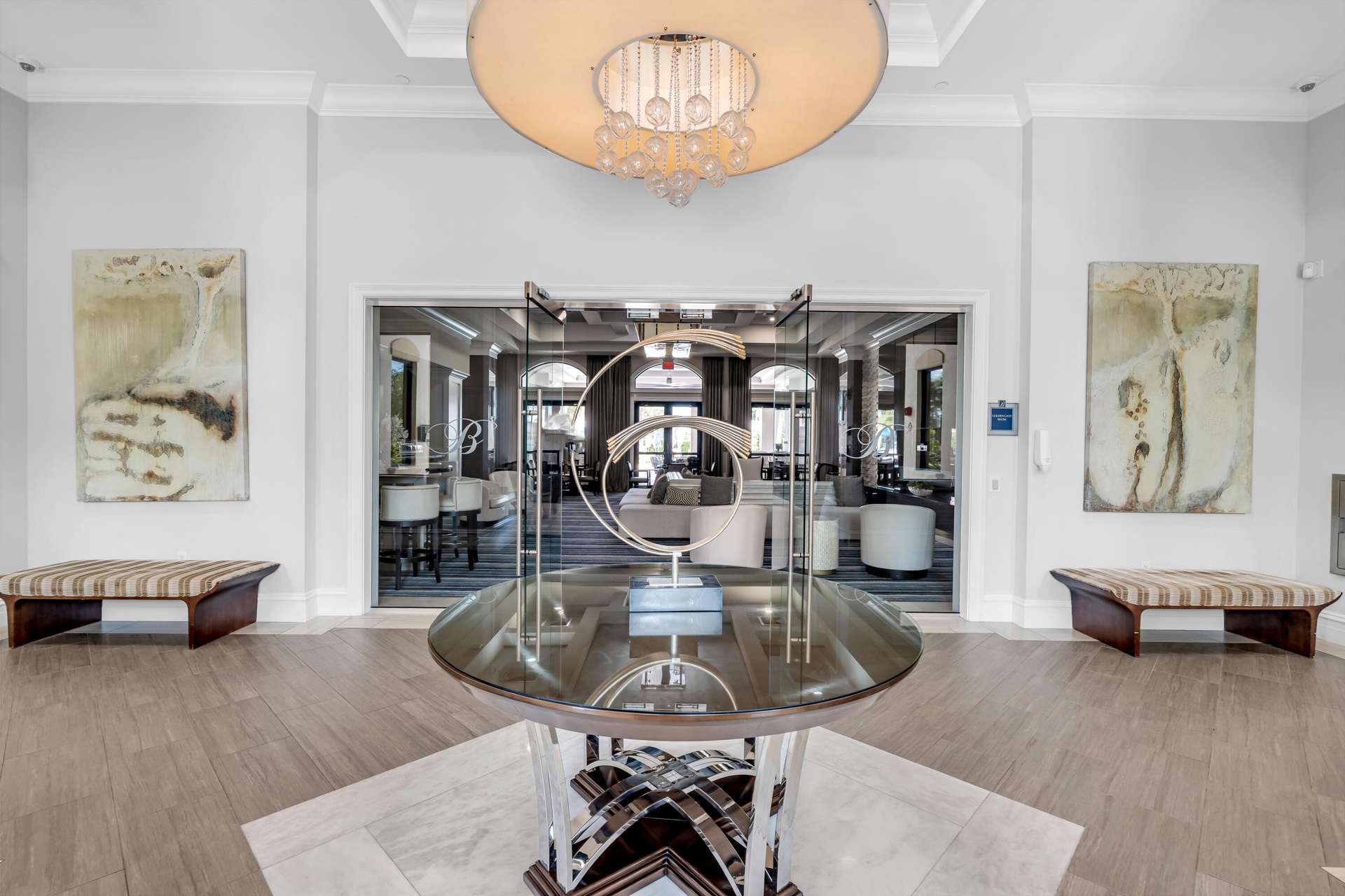 Spacious entry foyer featuring wood-finish flooring, a contemporary chandelier, crown molding, and a central round glass-top table