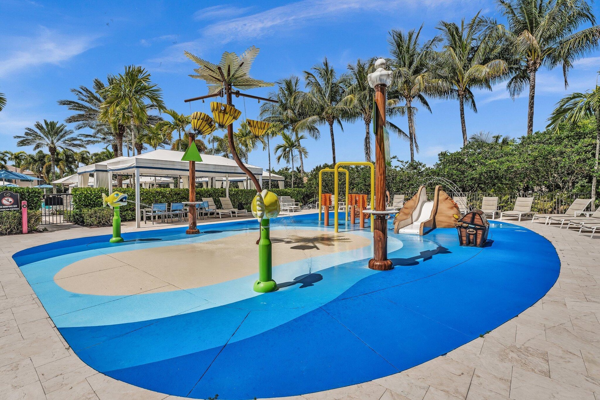 Vibrant splash pad featuring multiple water play structures, a small slide, and a durable blue and tan surface