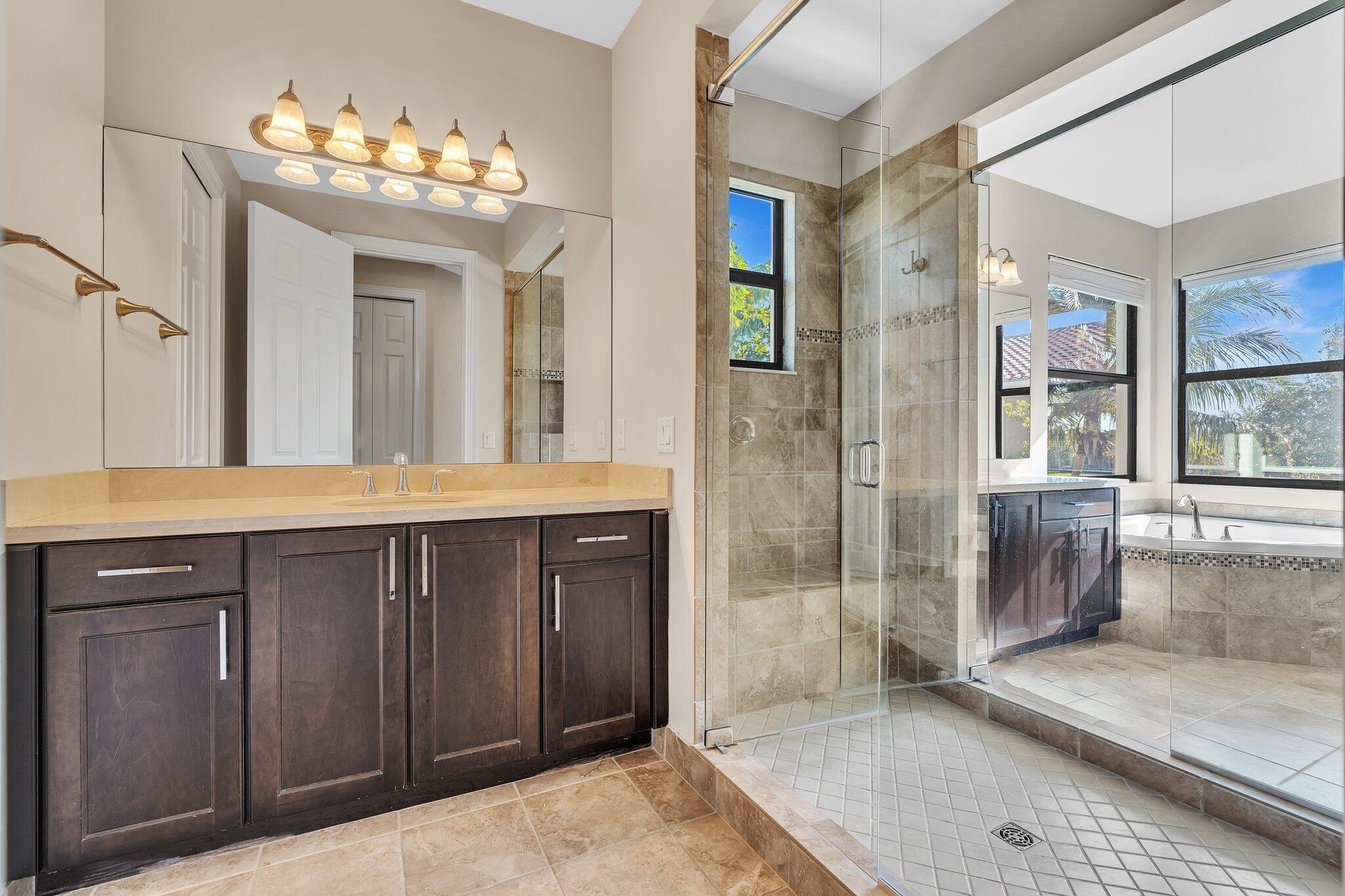 Spa-inspired primary bathroom featuring a double vanity with dark cabinetry and wood-finish countertop, paired with a large walk-in shower encased in 