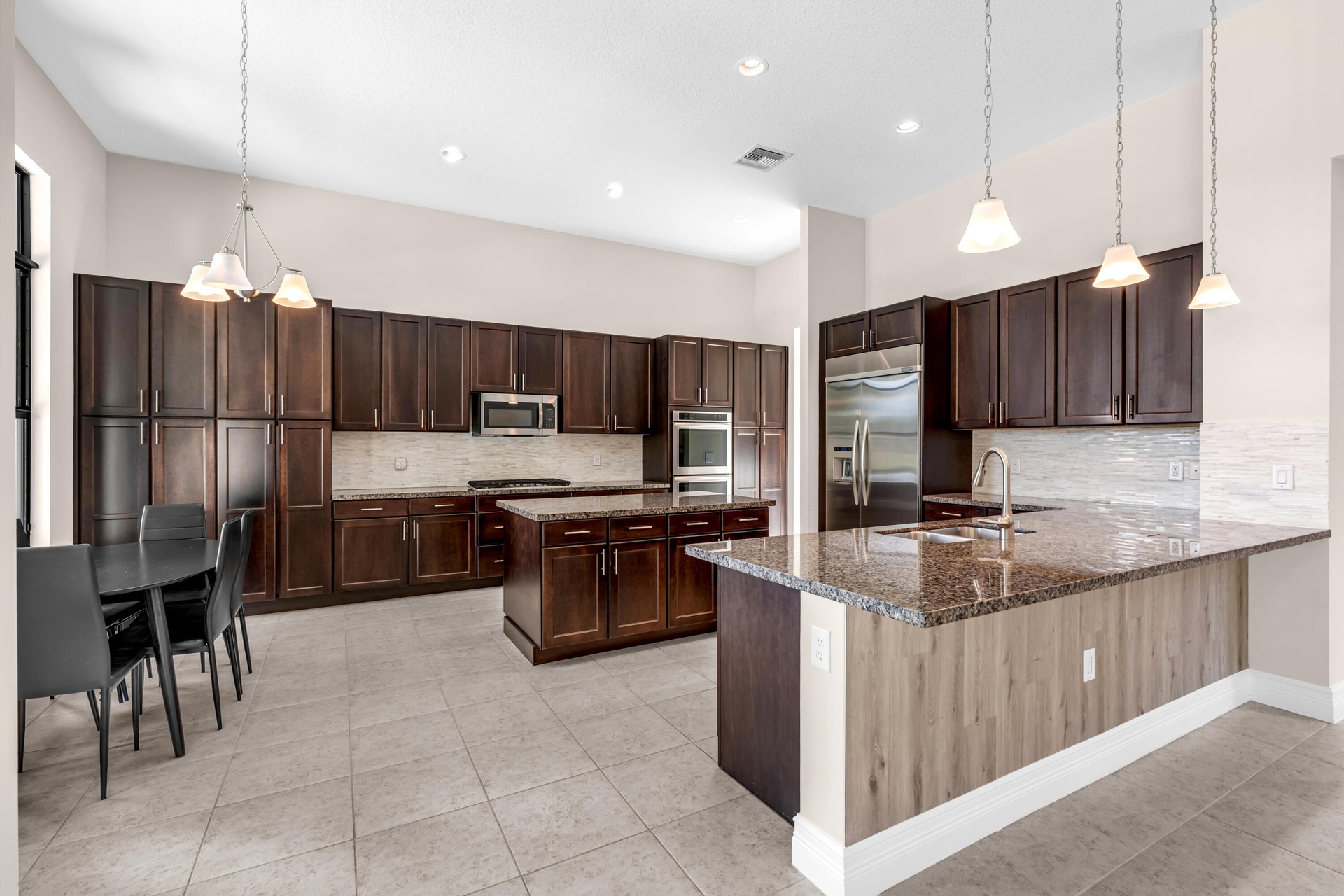 Gourmet kitchen featuring dark wood cabinetry, stainless steel appliances, and a large center island with wood-finish base and granite countertop
