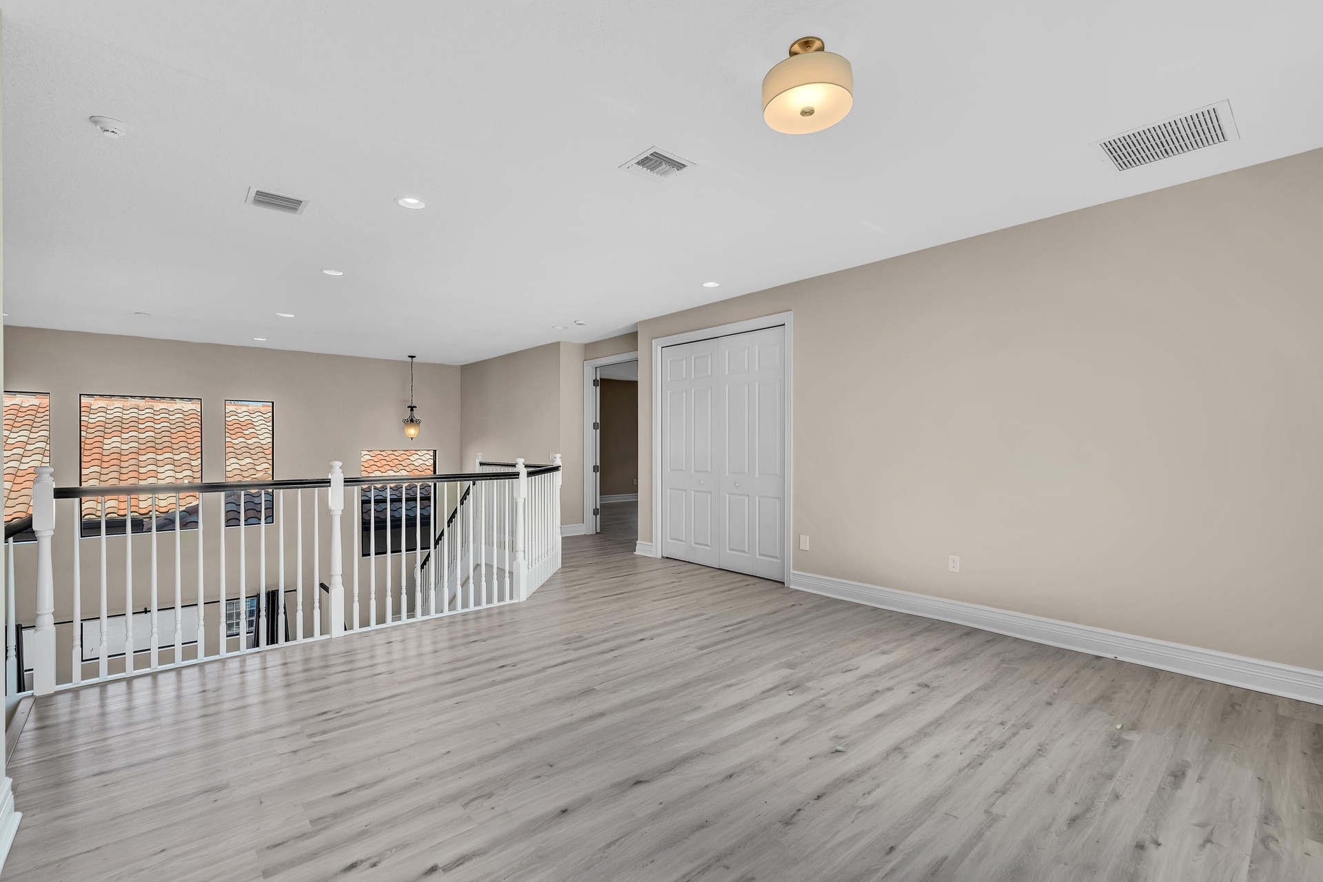 Open concept bonus area featuring light wood-finish flooring, white baseboards, and neutral wall tones