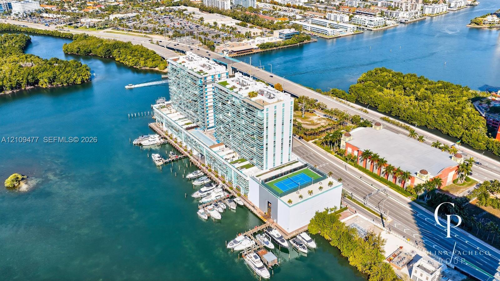 High-rise coastal property featuring deep-water marina slips, rooftop tennis court, expansive glass-paneled balconies, and manicured terrace landscapi