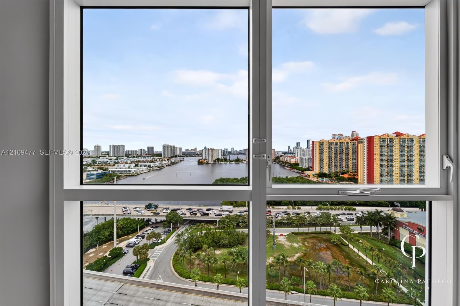 Oversized picture windows with white frames featuring panoramic exposure of the waterway, urban skyline, and surrounding landscape