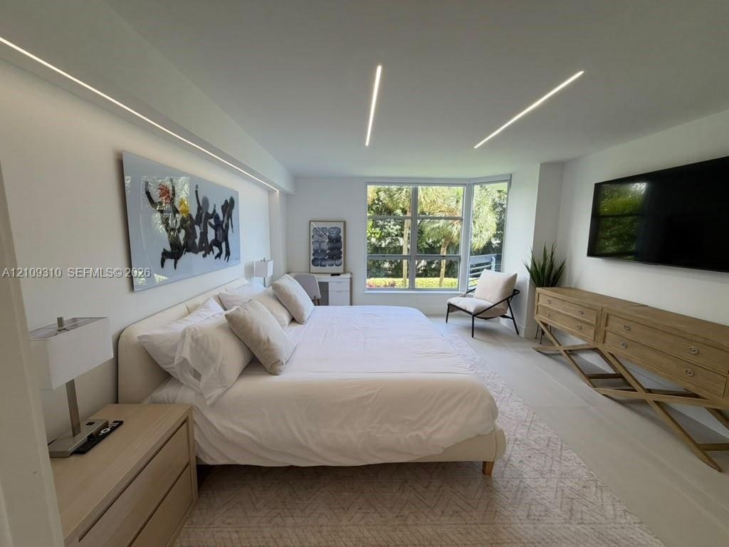 Neutral-toned room featuring expansive floor-to-ceiling windows, modern recessed linear ceiling lighting, wall-integrated cove lighting, and light-ton