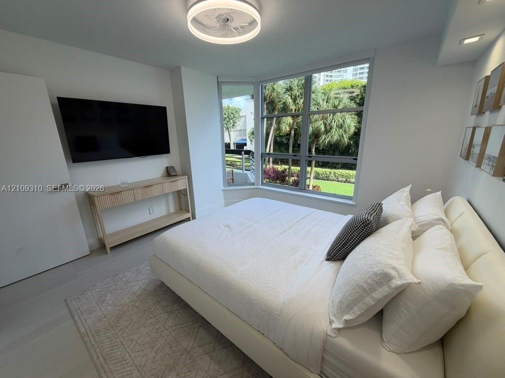 Bay window with multi-pane glass, recessed ceiling lighting, circular flush-mount light fixture, and light-toned flooring