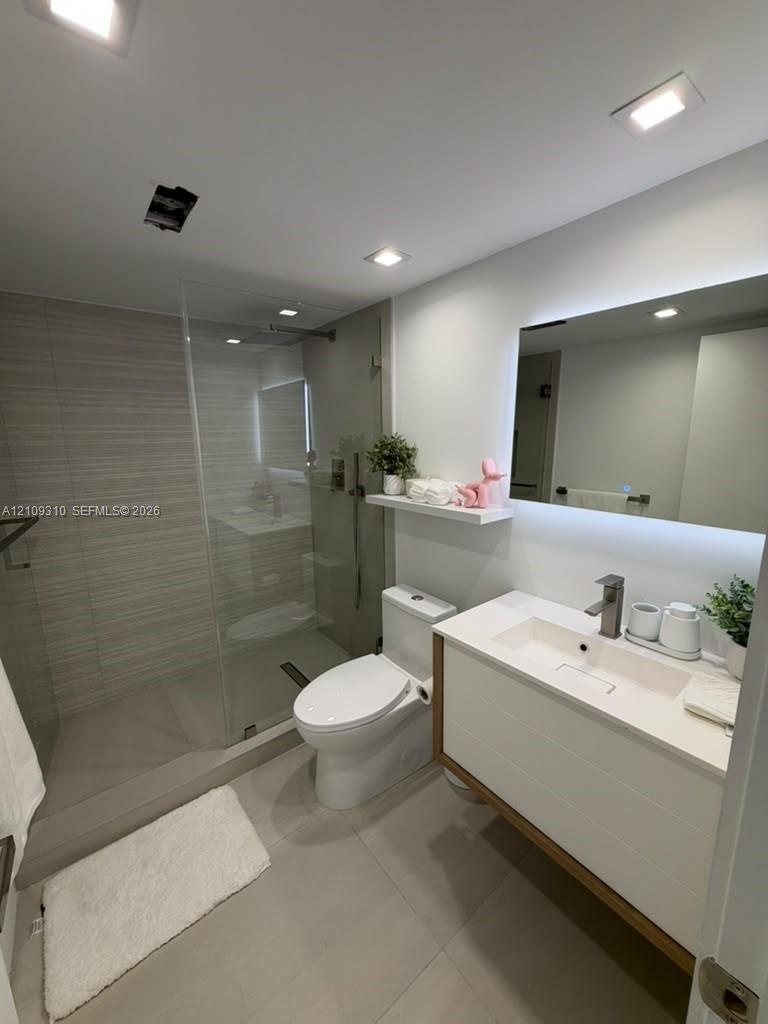 Walk-in shower with horizontal tile surround and glass partition, floating vanity featuring a rectangular integrated sink, white countertop, and LED-b