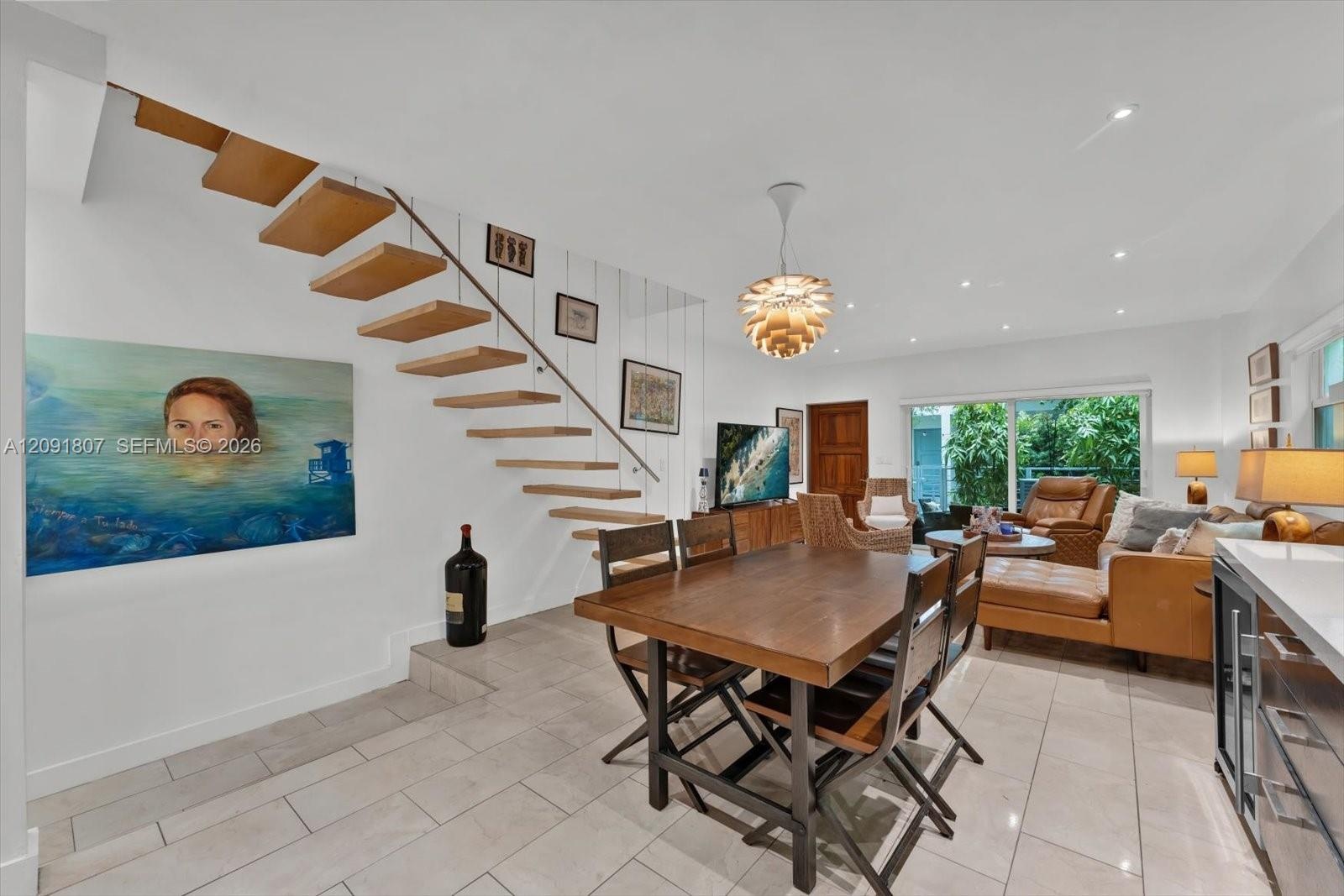 Open-concept area featuring a floating staircase with wood treads, light-toned ceramic tile flooring, recessed lighting, a modern spherical pendant li