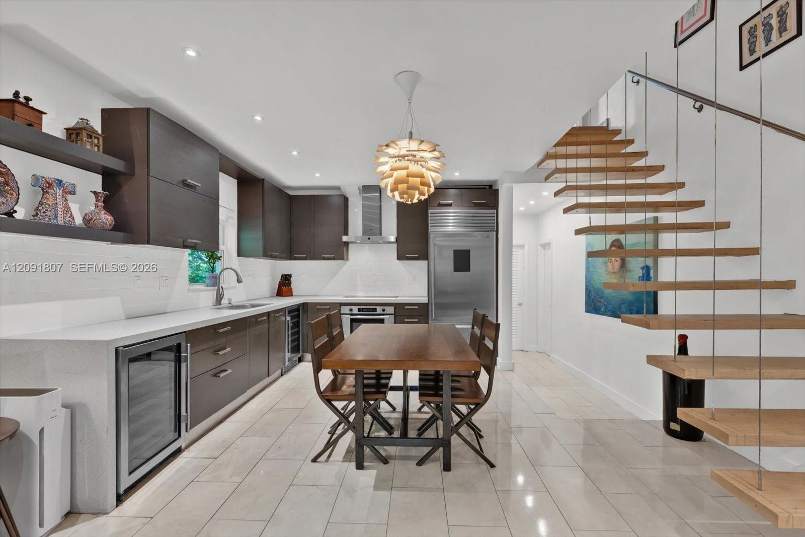Custom cabinetry with horizontal hardware, light-toned stone tile flooring, stainless steel integrated refrigeration, stone-surfaced countertops, and 