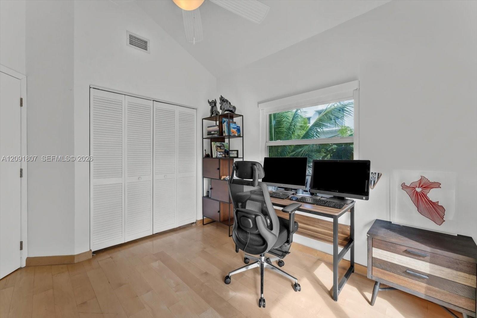 Vaulted ceilings, wood-finish flooring, and white louvered-door closet featuring a ceiling fan and natural lighting