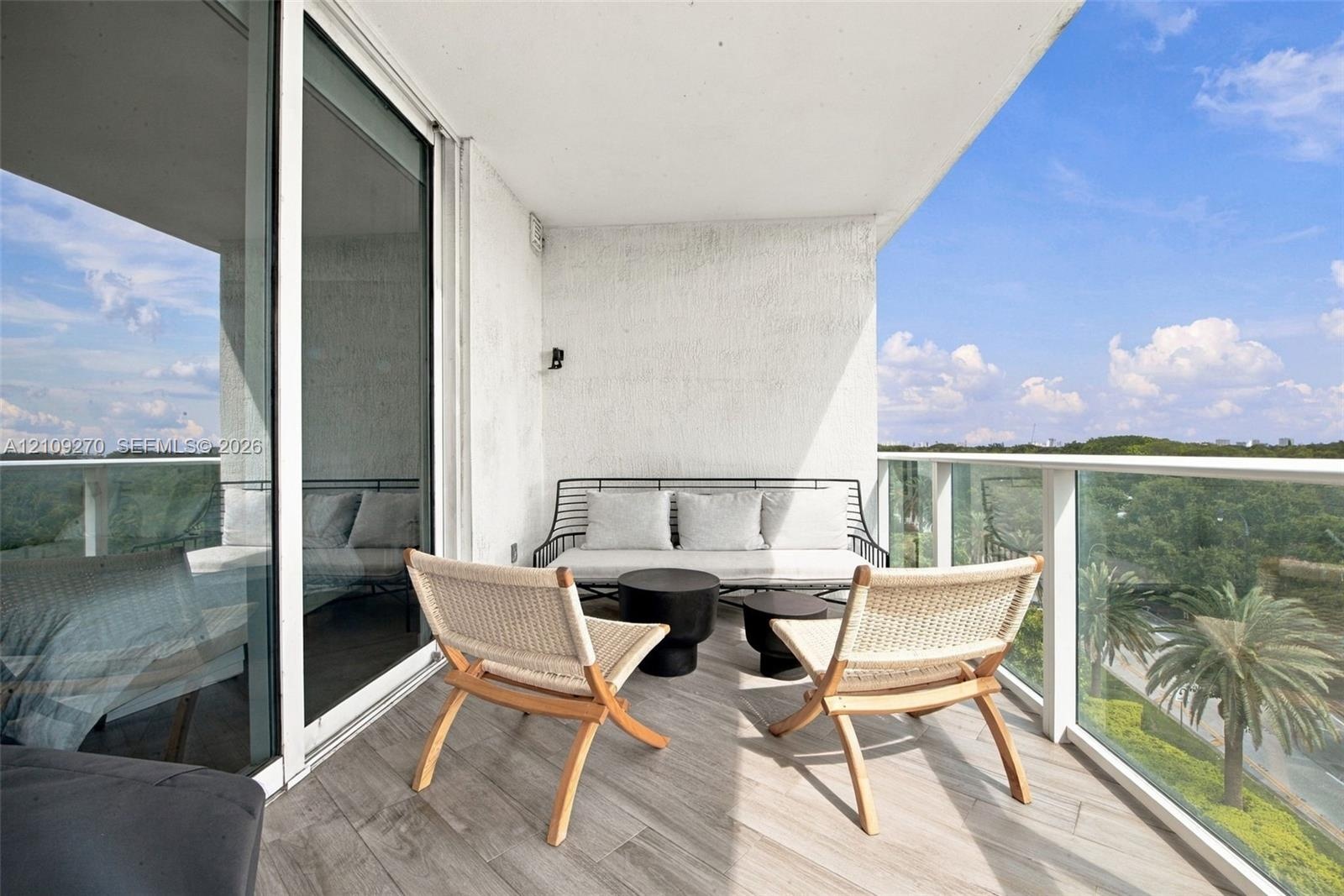 Private balcony featuring wood-finish flooring, glass panel railings, and full-height sliding glass doors