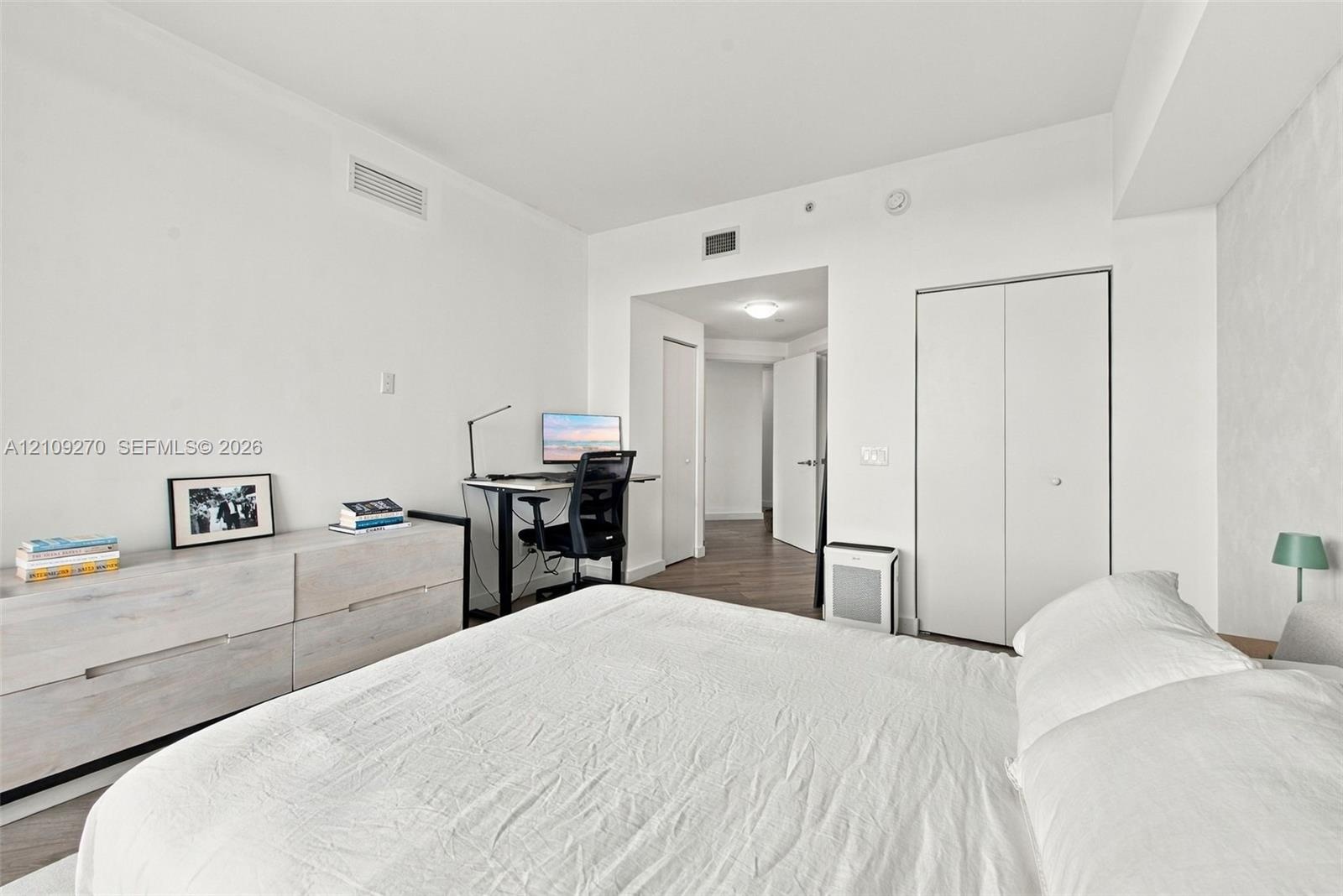 Room featuring wood-finish flooring, white walls, and a closet with double-panel doors