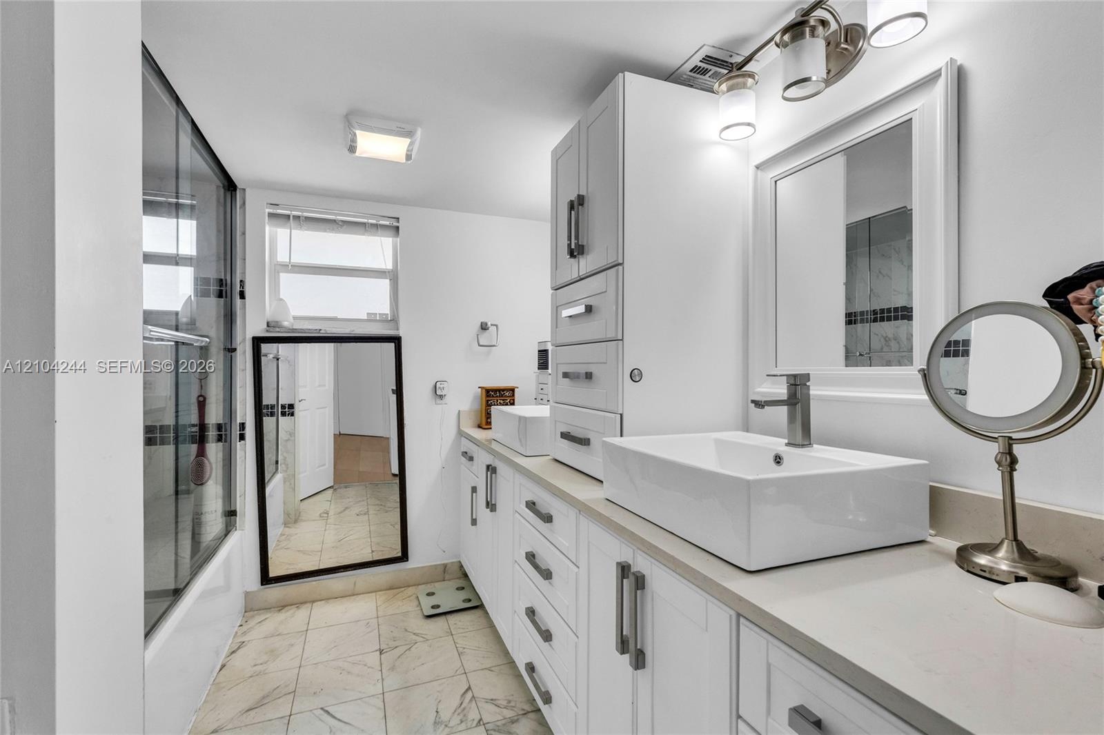Bathroom featuring dual rectangular vessel sinks, stone-finish countertops, and a walk-in shower with a framed glass enclosure