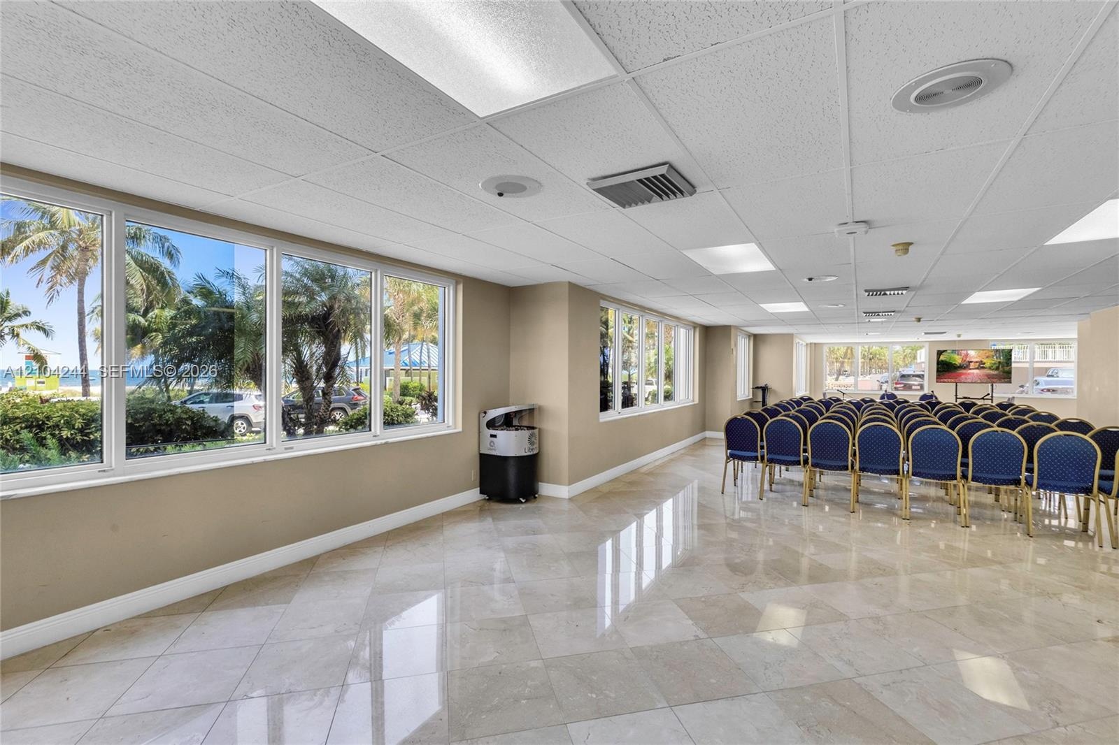 Open-concept interior featuring polished stone flooring, expansive floor-to-ceiling windows, and recessed ceiling lighting