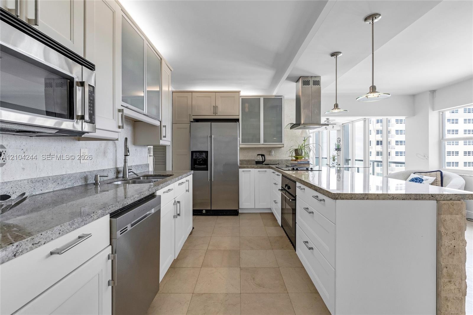 Kitchen featuring flat-panel cabinetry, stone countertops, stainless steel appliances, a center island with pendant lighting, and tile flooring