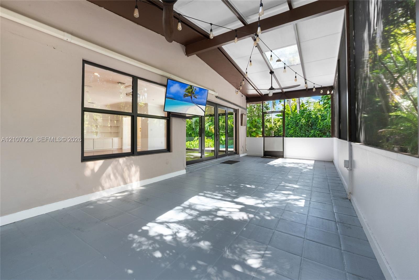 Screened patio featuring tile flooring, a skylight, exposed wood-beam ceiling, and sliding glass doors