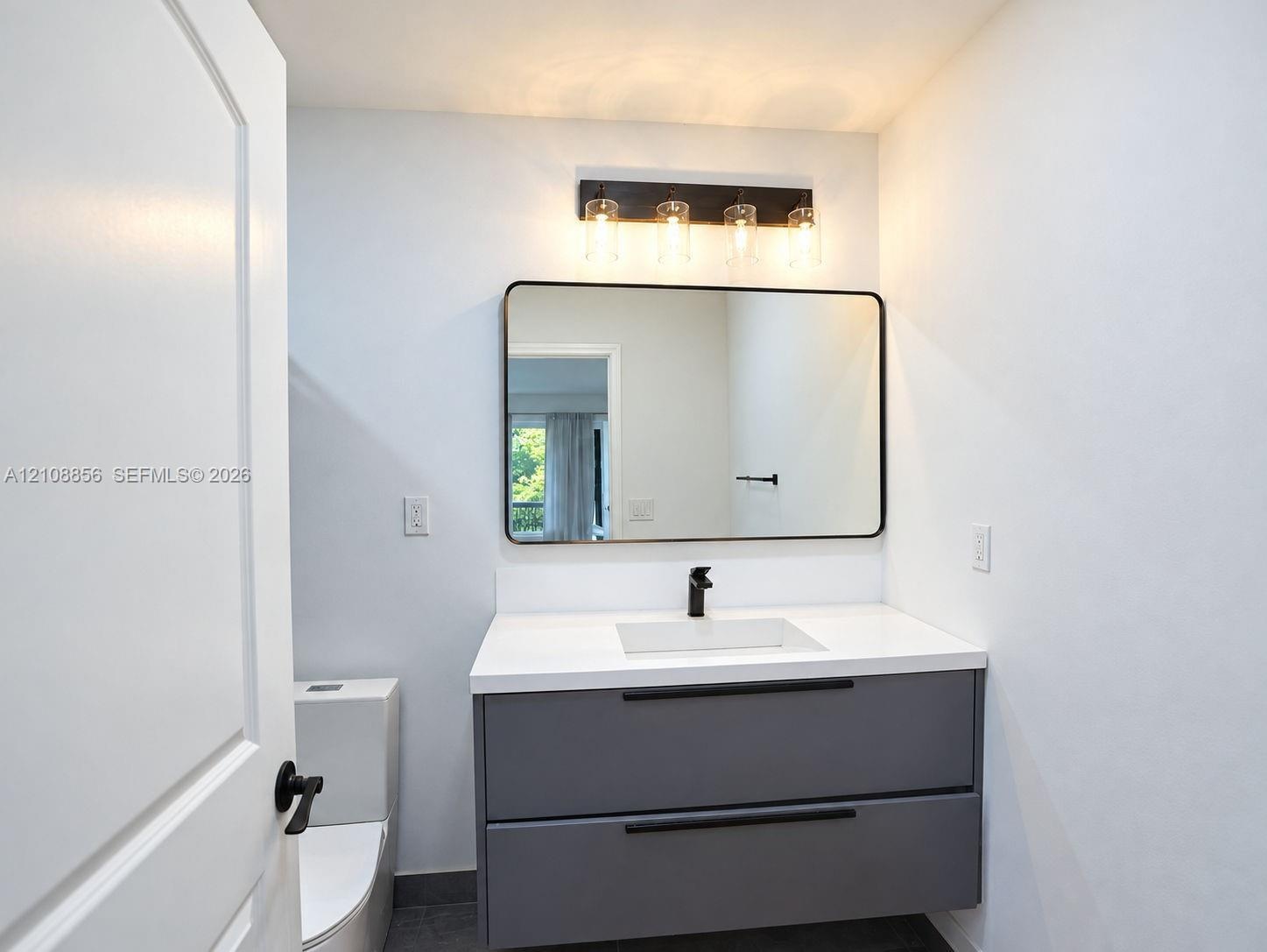 Floating vanity with matte finish charcoal cabinetry, white countertop, rectangular integrated sink, wall-mounted matte black faucet, and rectangular 