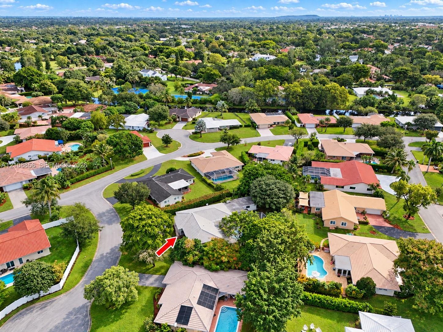 Aerial perspective of a suburban neighborhood featuring tree-lined streets, landscaped lots, and proximity to green space