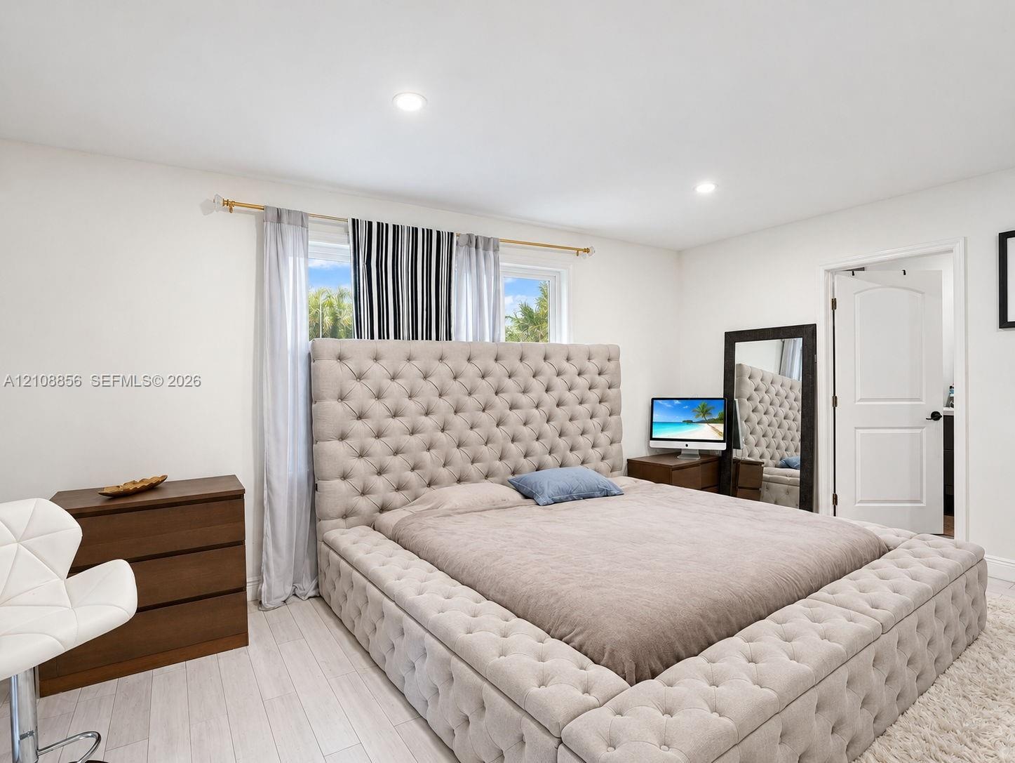 Neutral-toned wood-finish flooring, recessed lighting, and a multi-panel interior door