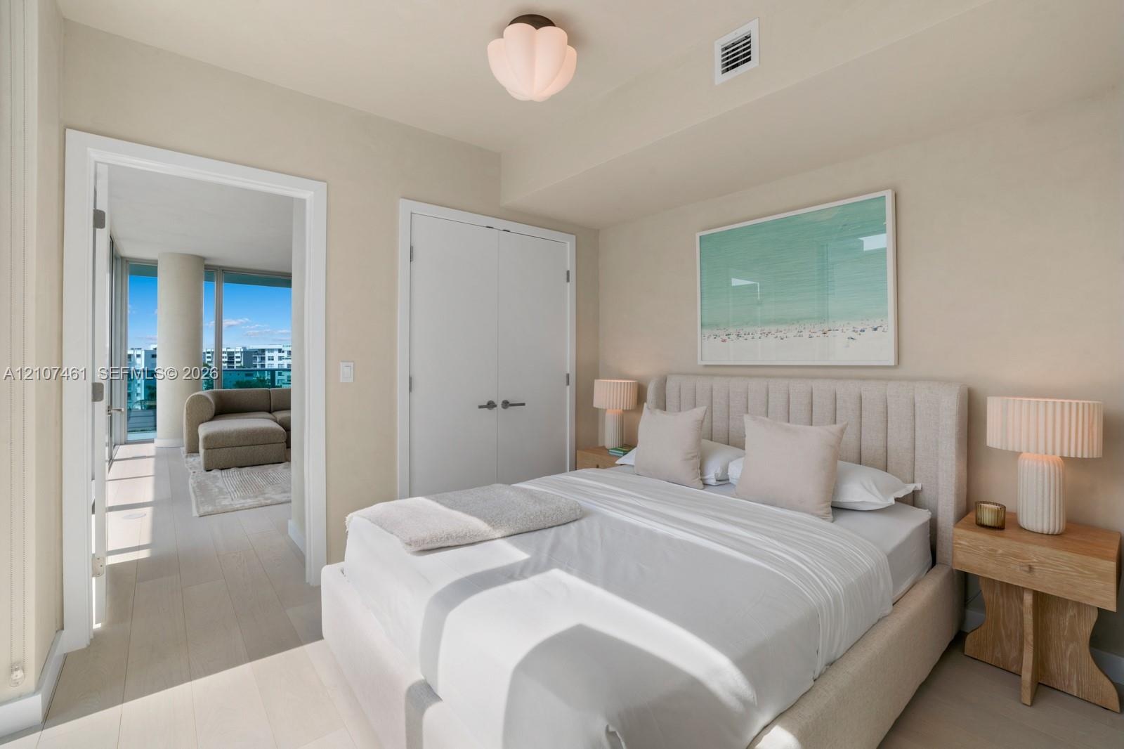 Light-toned wood-finish flooring, white double-door closet with modern hardware, and decorative petal-shaped ceiling light fixture