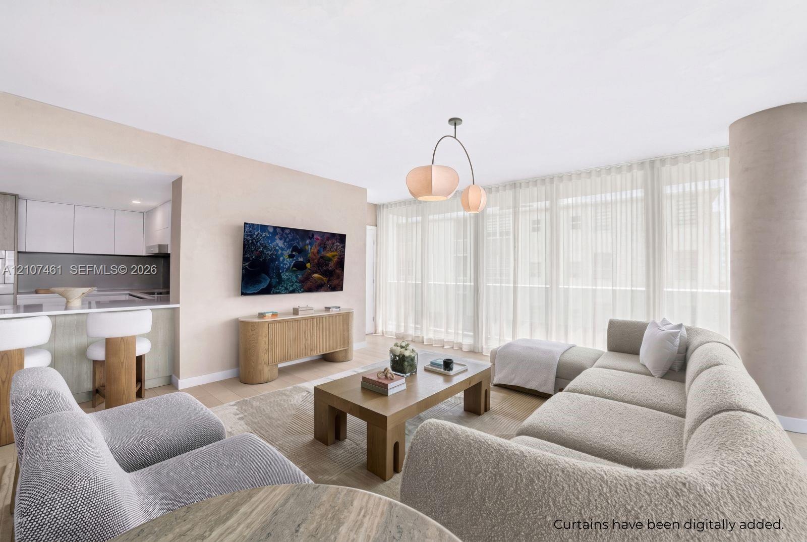 Open-concept living space featuring wood-finish flooring, floor-to-ceiling windows, a modern multi-arm pendant light, and a peninsula kitchen with fla