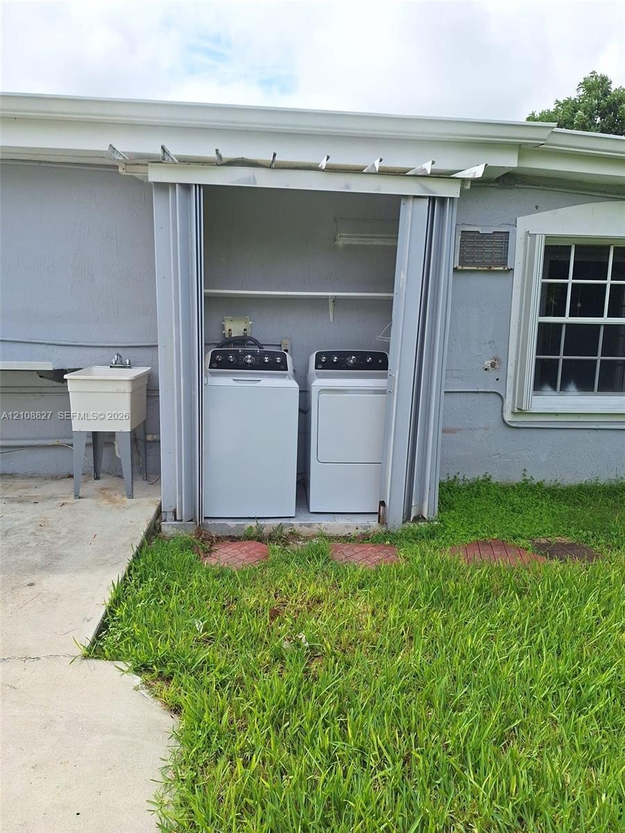 Exterior laundry alcove featuring folding privacy doors, built-in shelving, and a utility sink