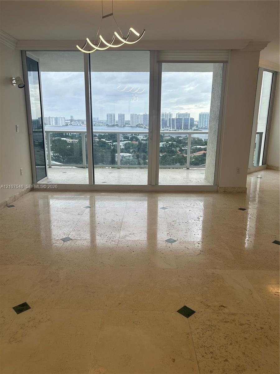 Polished stone flooring with decorative inlays, expansive floor-to-ceiling glass sliding doors, private balcony, contemporary geometric pendant lighti