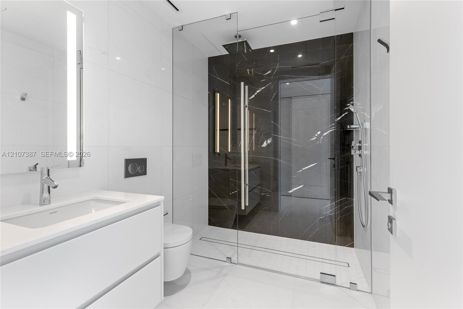 Modern bathroom featuring a floating white vanity with a rectangular sink, wall-mounted faucet, walk-in shower with floor-to-ceiling glass enclosure, 